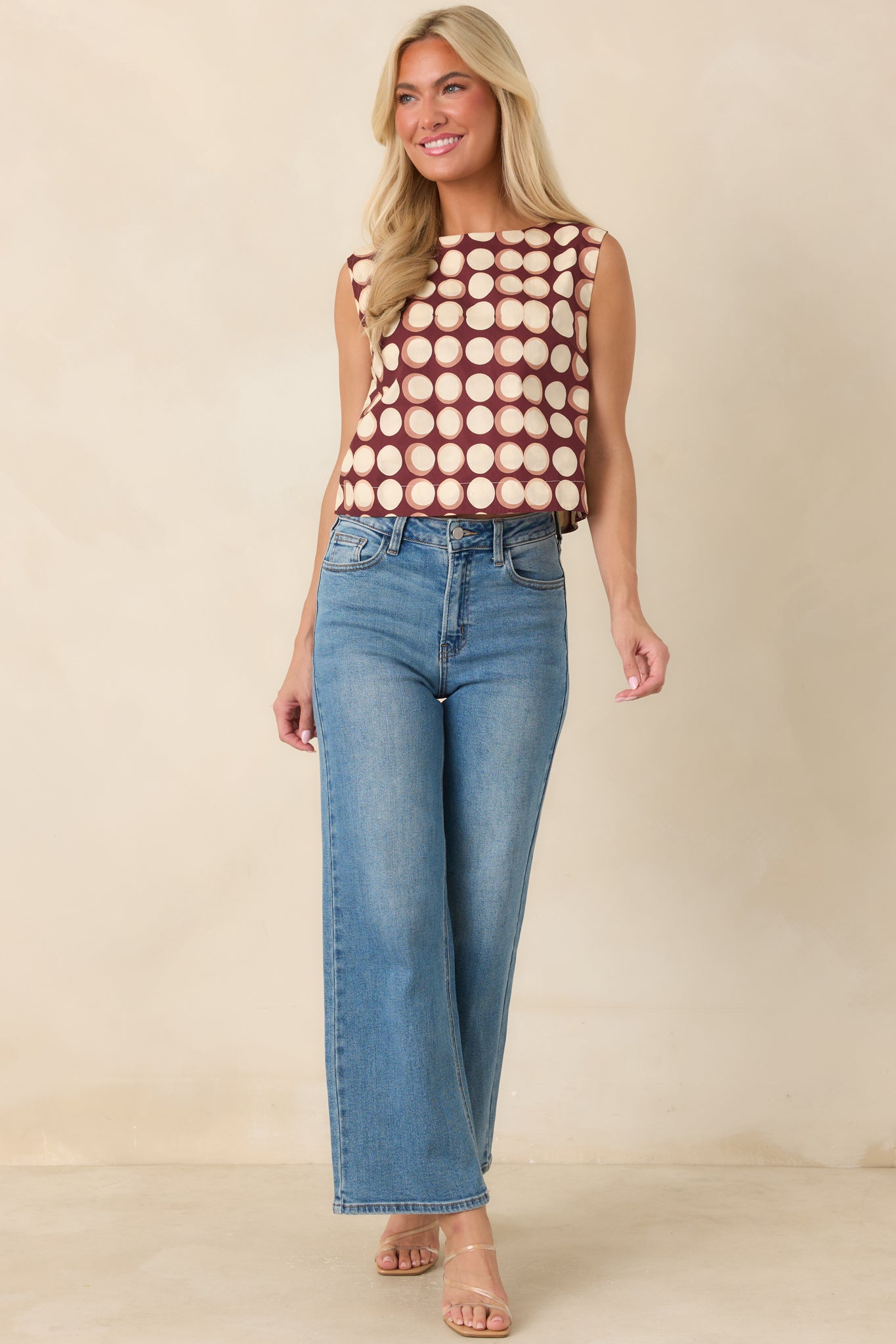 Burgundy cropped top featuring an allover abstract dot print, sleeveless construction, and streamlined boat neckline for a polished finish.