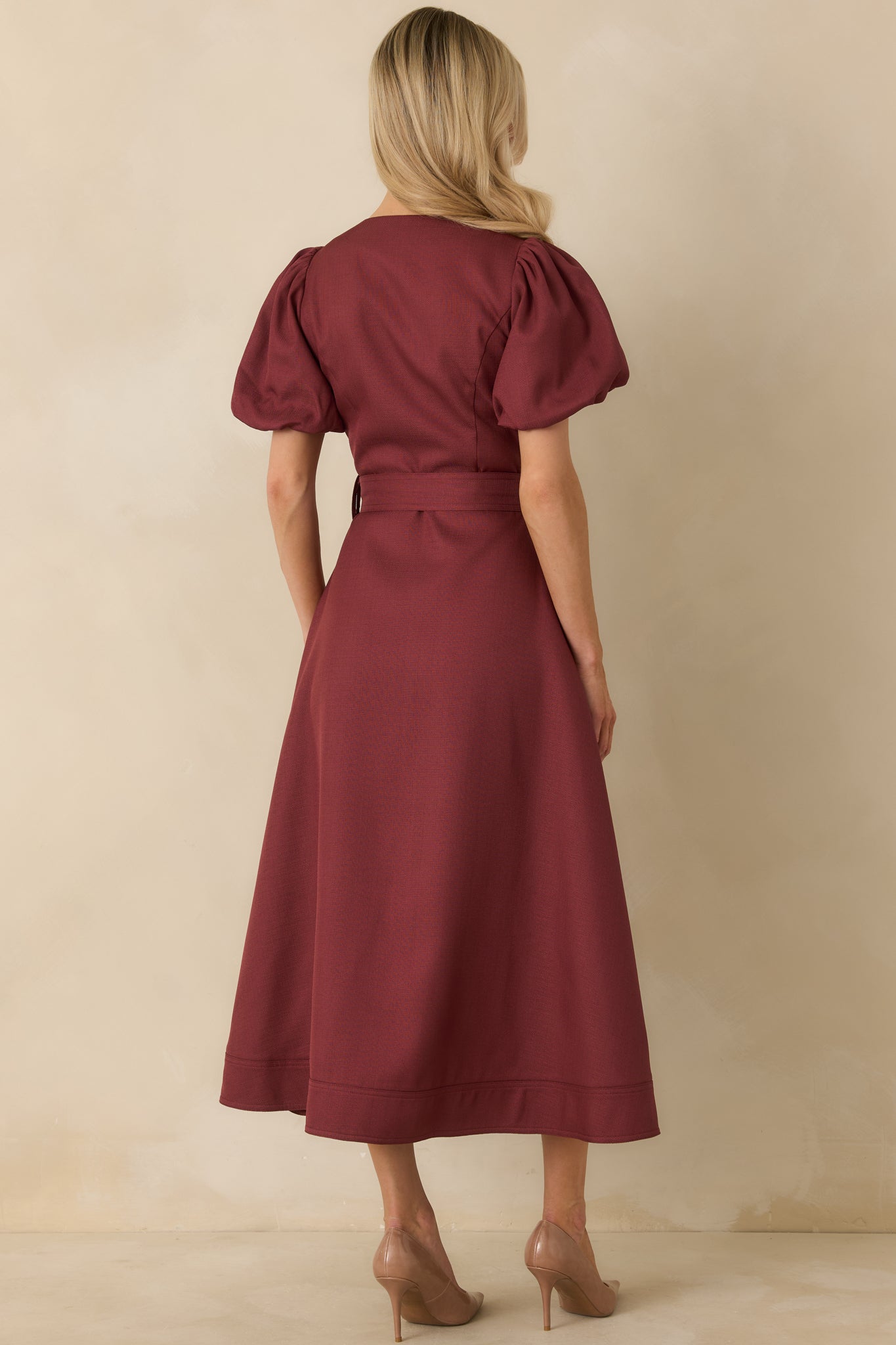 Back view of burgundy midi dress with structured puff sleeves, a fitted waist with removable belt, and flared A-line skirt.