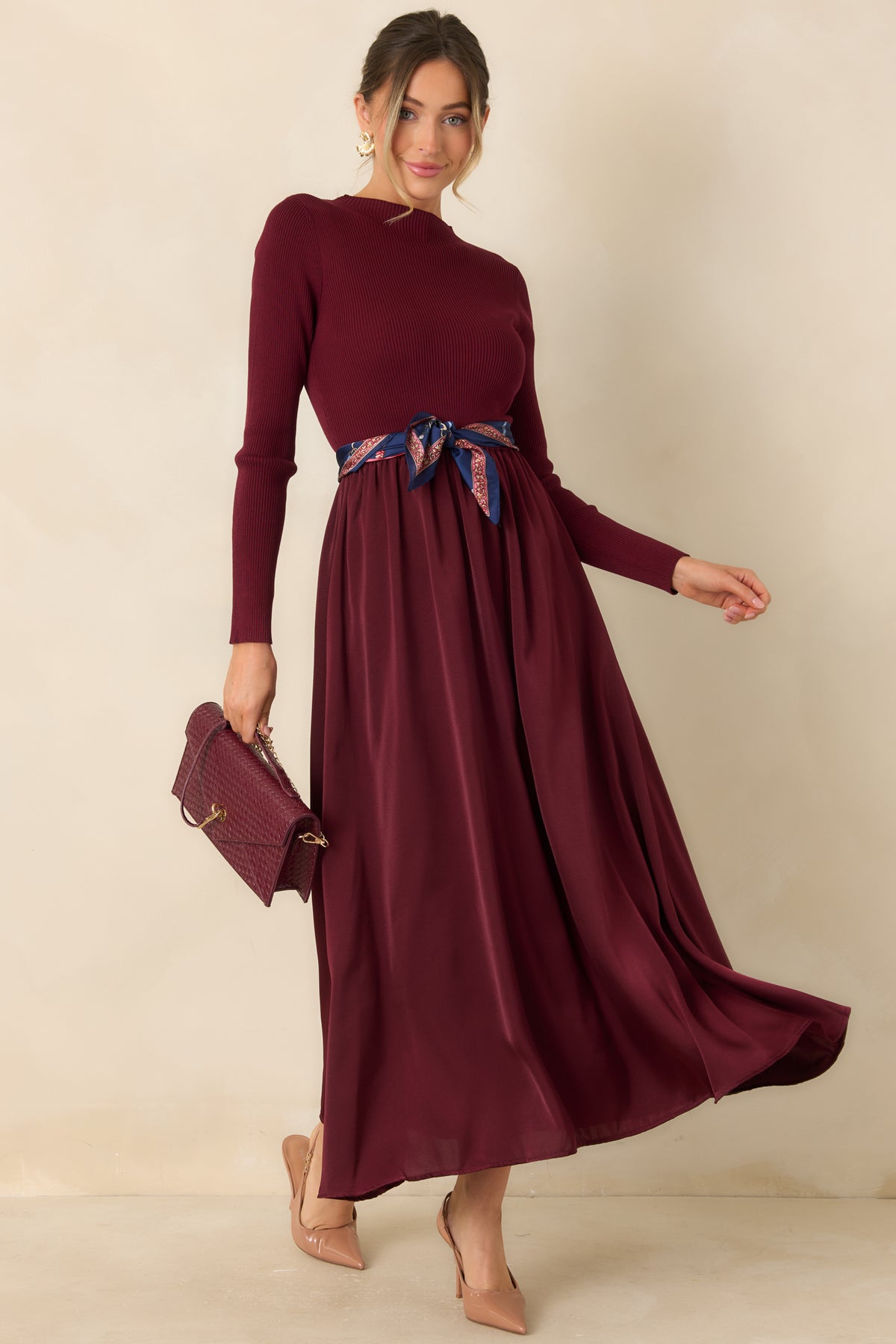 Burgundy fit-and-flare dress with a fitted ribbed knit bodice, long sleeves, and a flowing satin skirt.