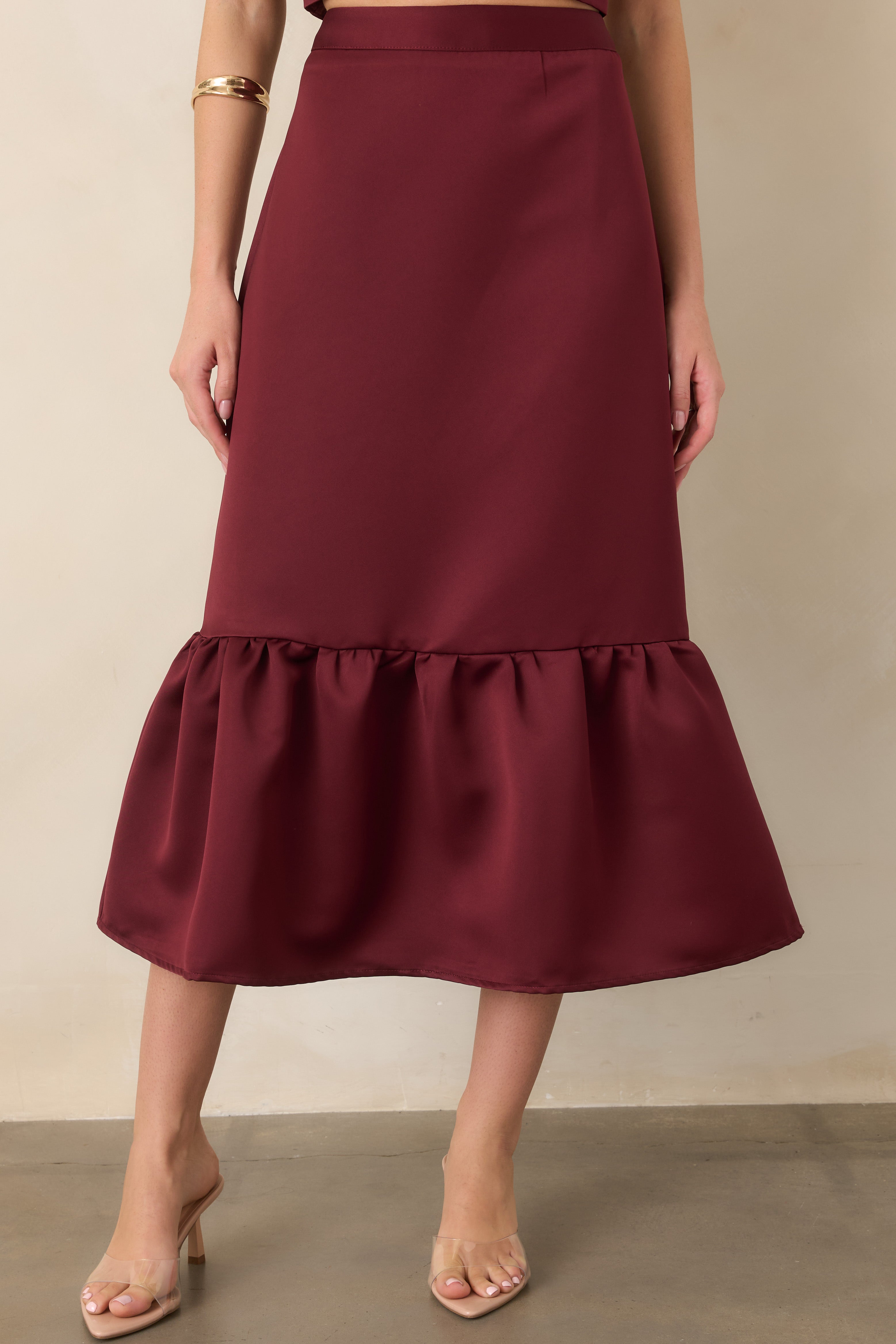 Detailed view of the skirt showcasing the rich burgundy satin fabric and layered flounce that adds soft volume to the streamlined shape.