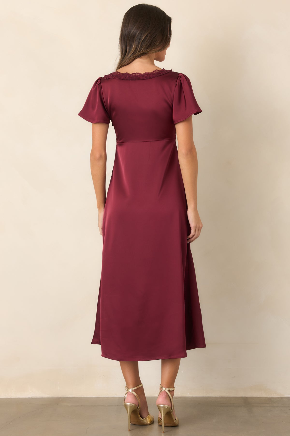 Rear view of the burgundy satin midi dress showing the gathered bodice, flutter sleeves, and concealed side zipper design.