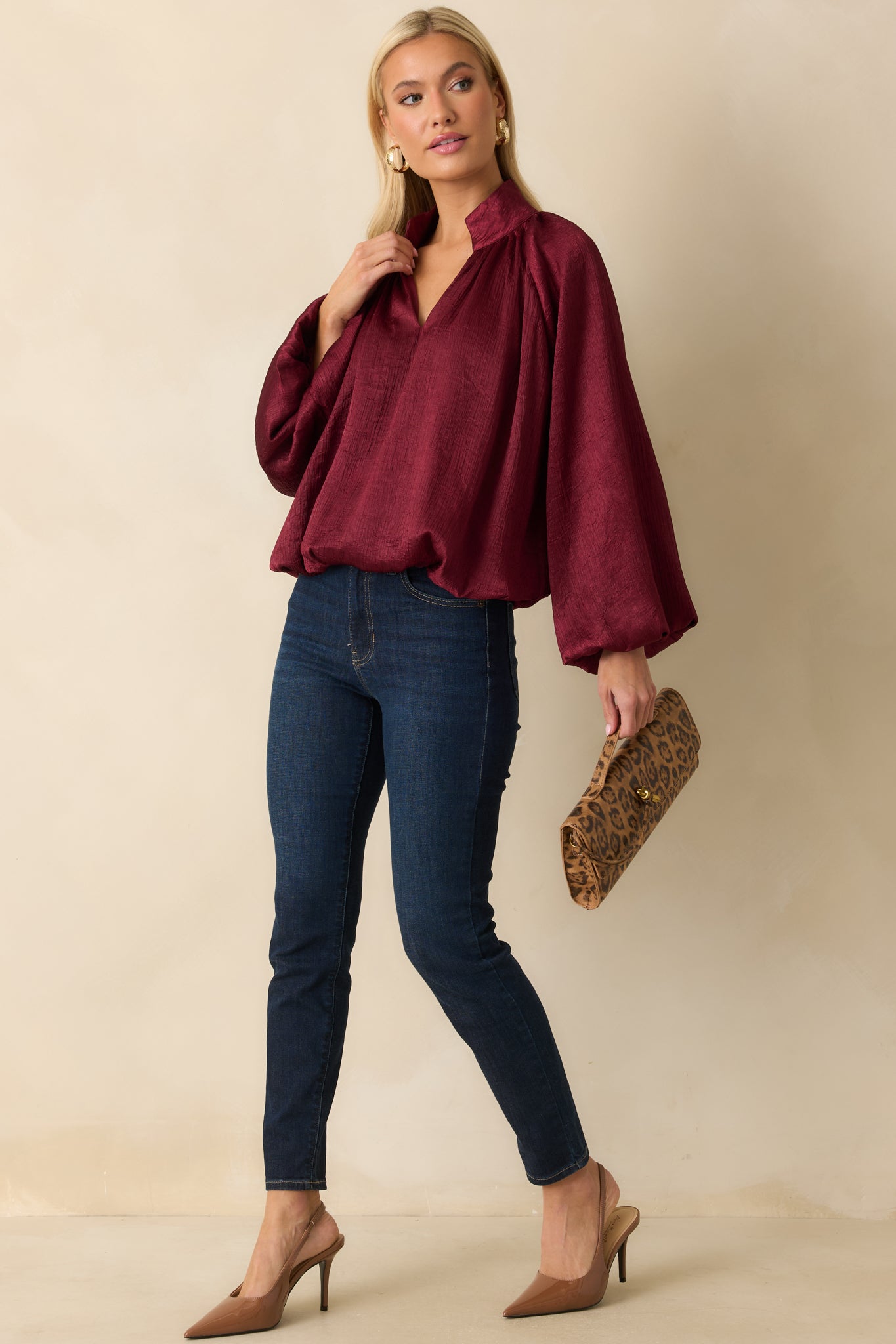 Burgundy satin V-neck top with long peasant sleeves, gathered cuffs, and a relaxed, subtly textured silhouette.