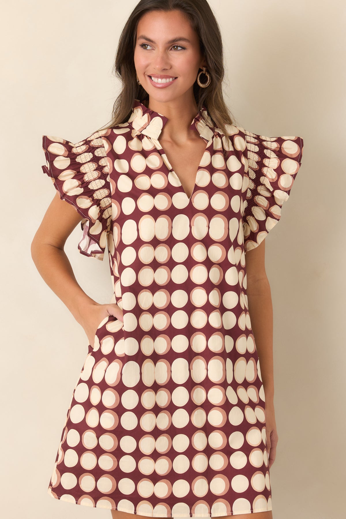 Relaxed burgundy shift mini dress with softly outlined ivory dots and feminine ruffled detailing around the neckline and sleeves.