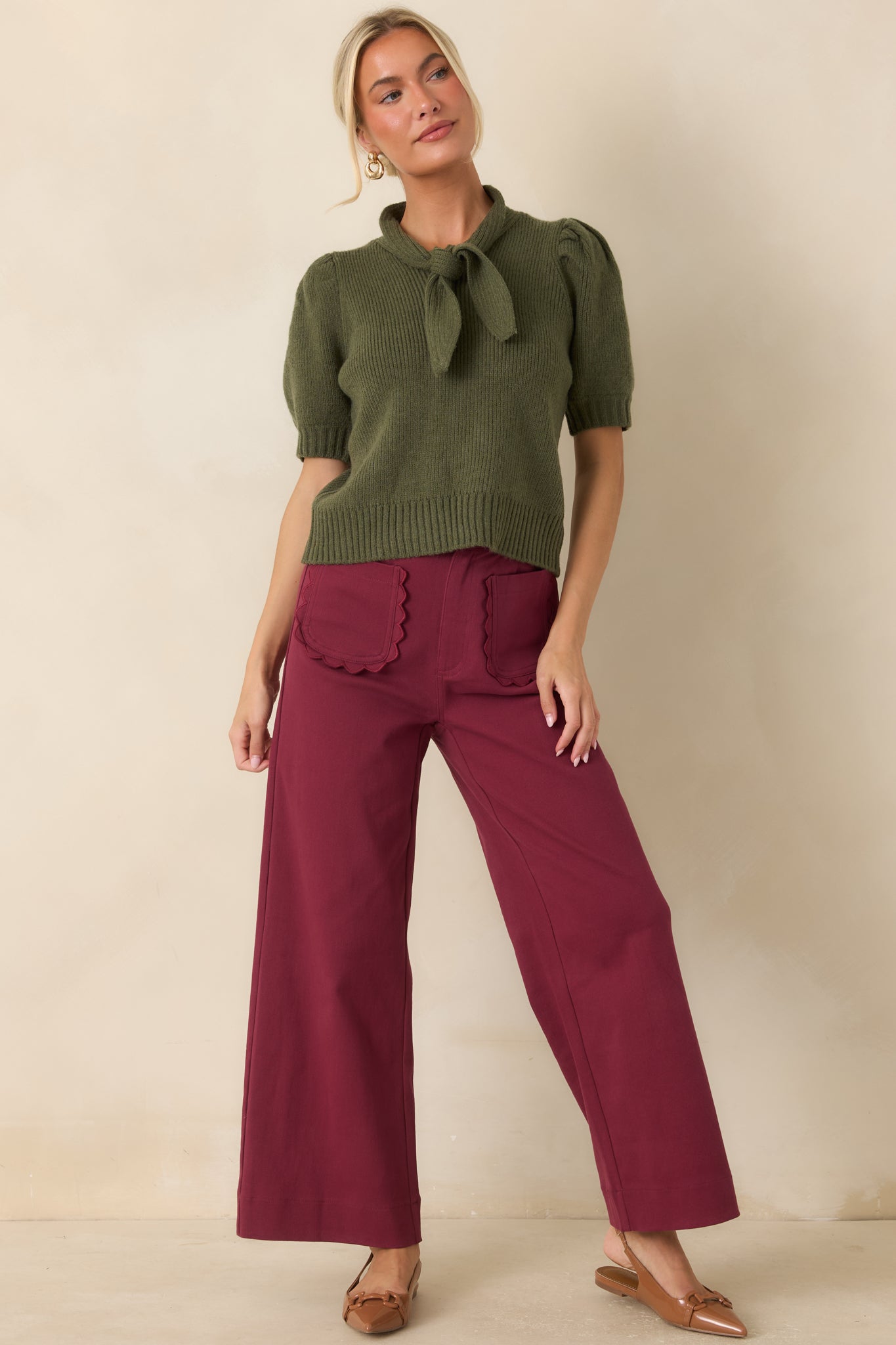 Deep burgundy tailored pants featuring a high-rise waist, wide-leg silhouette, scalloped front patch pockets, and polished finish.