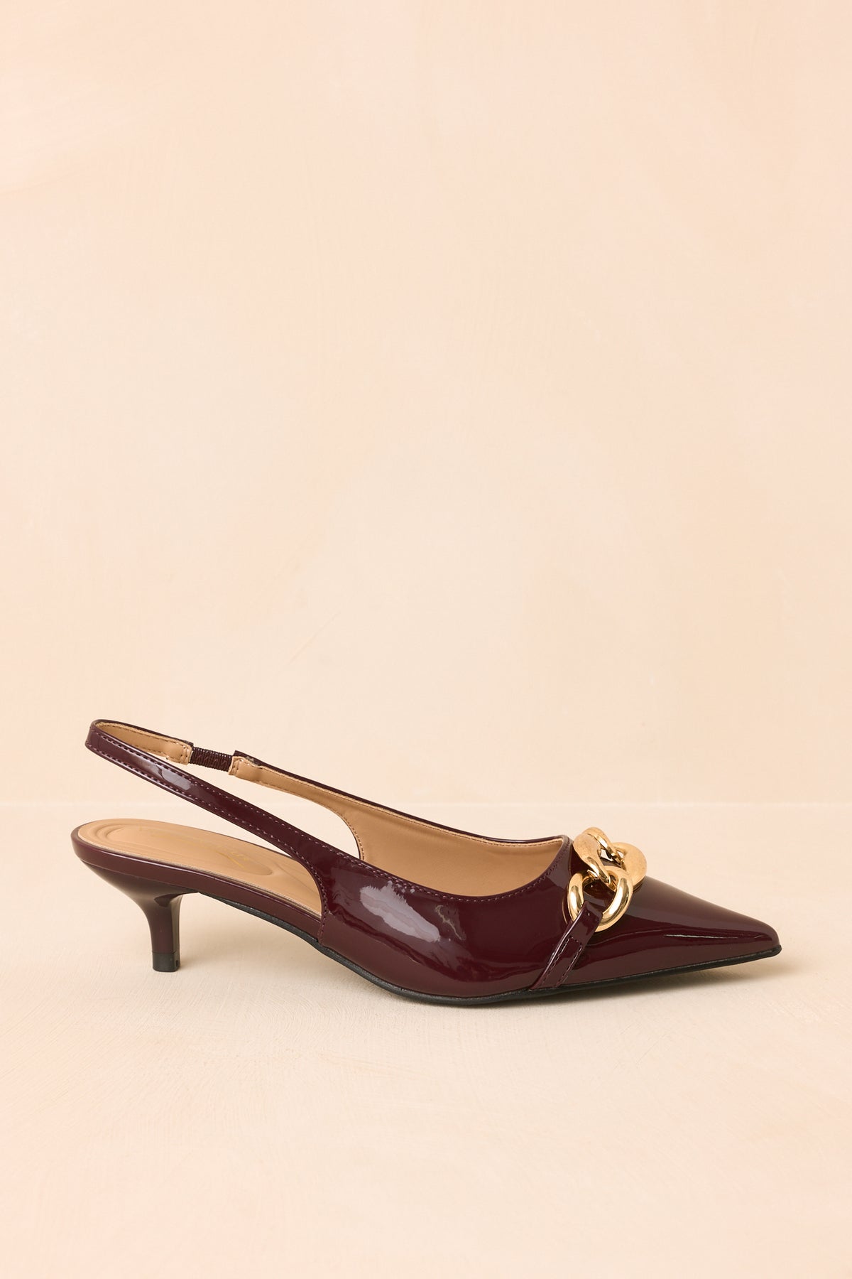 Patent slingback heels shifting between rich burgundy and wine tones with a pointed toe and sleek kitten heel.