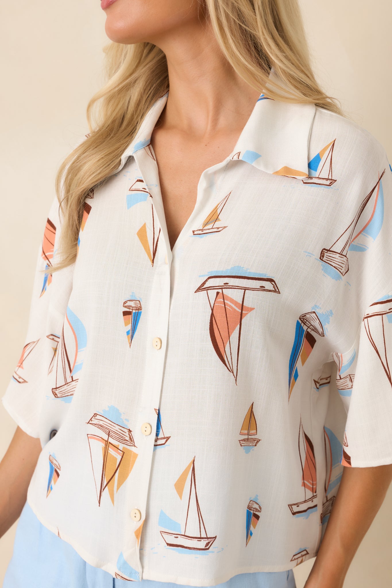 Close-up view of the button-front design, collar detail, and intricate sailboat print fabric.