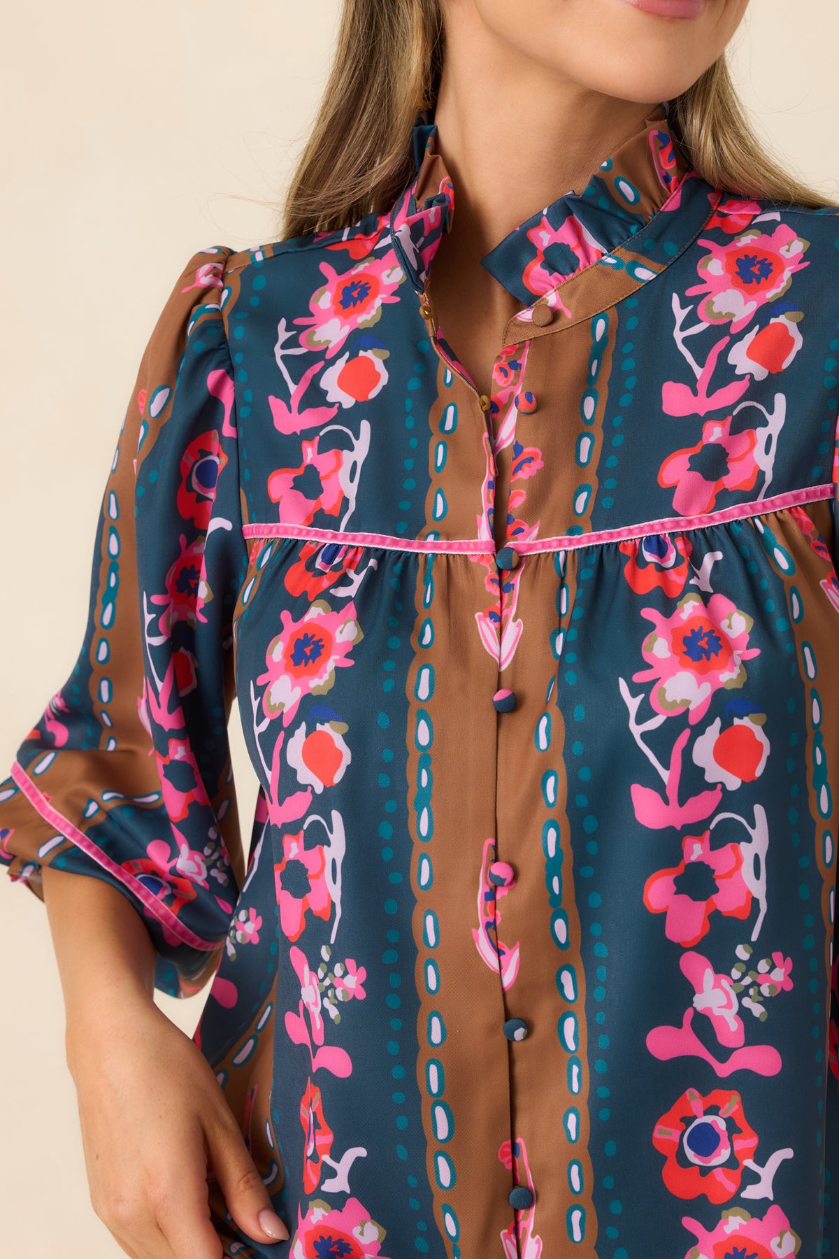 Fabric-covered buttons, pink trim, and a ruffled stand collar highlight the blouse's detailed floral stripe print.