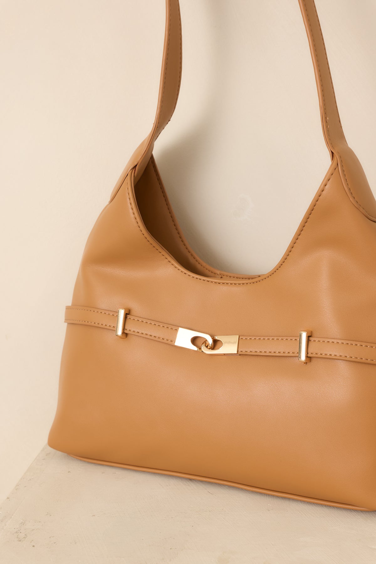 Close-up of the camel shoulder bag highlighting its smooth faux leather texture and polished gold-tone hardware details.