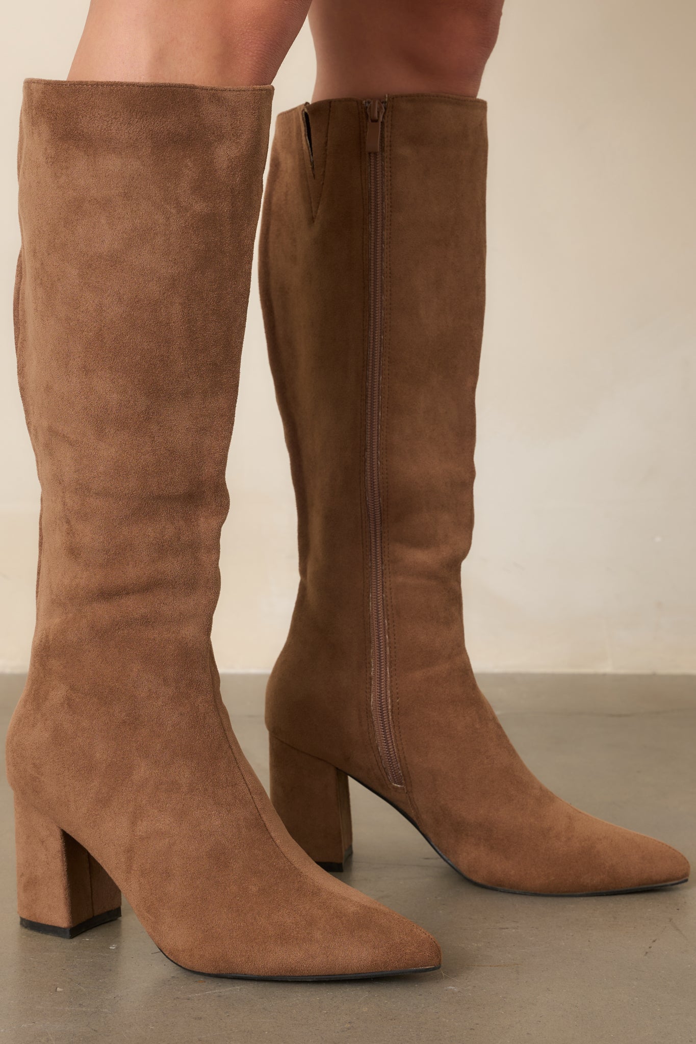 Close-up of the camel boots highlighting the smooth pointed toe, fitted shaft, covered block heel, and side zipper detail.
