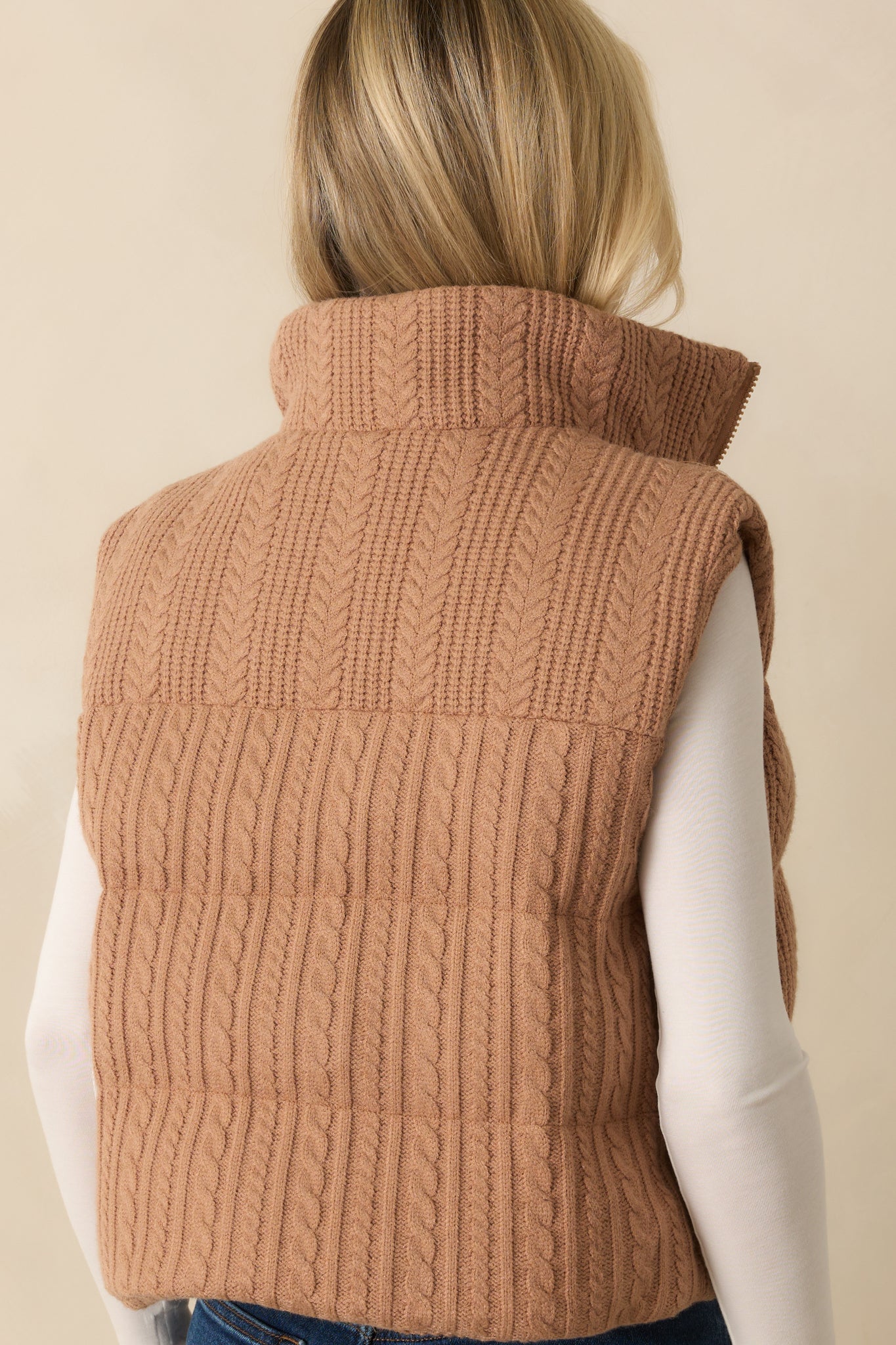 Rear view of the camel brown puffer vest with quilted cable knit design.