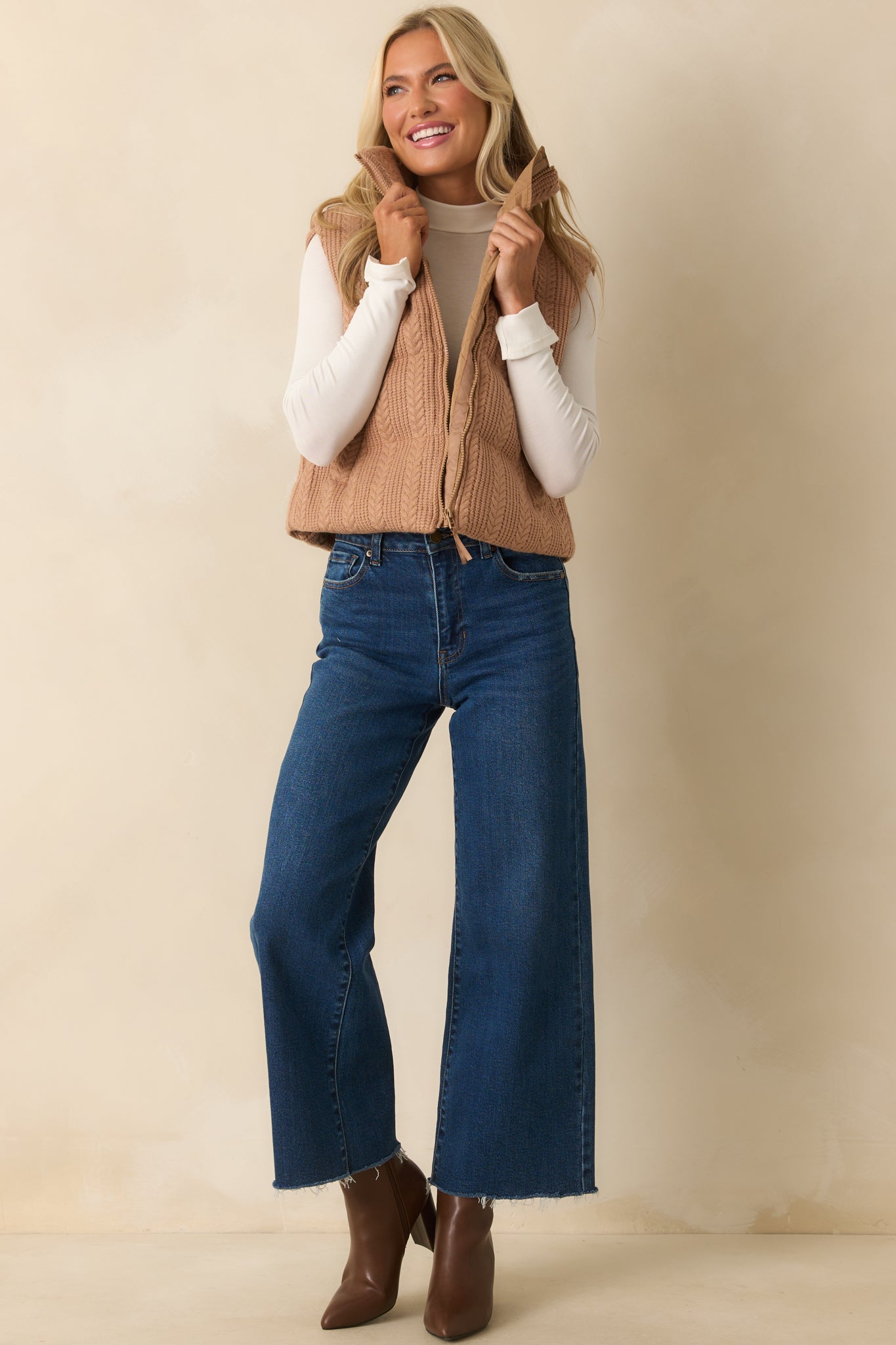 Sleeveless puffer vest in camel brown with front pockets and cable knit texture.