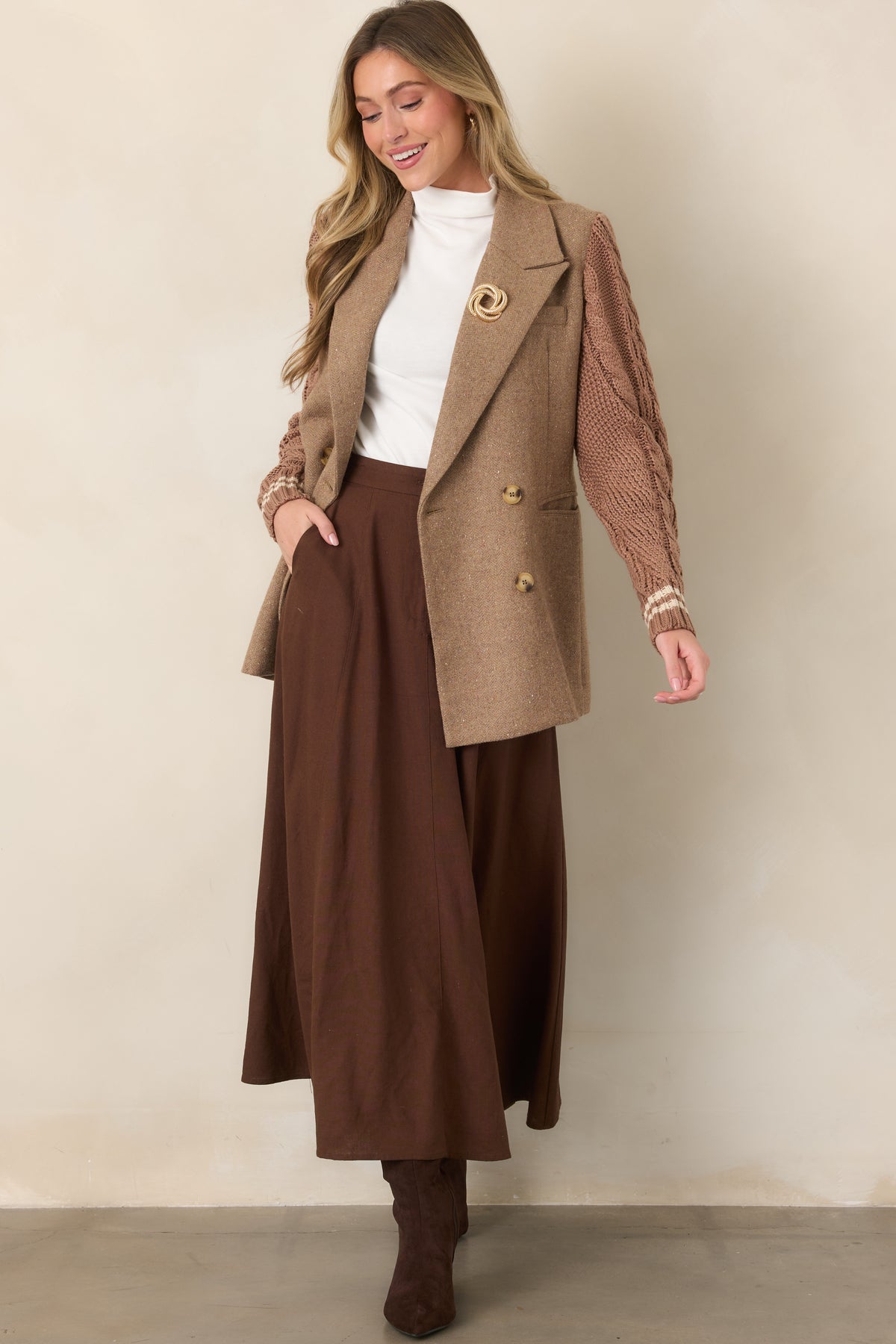 Structured camel blazer with a double-breasted button front, contrasting textured sleeves, striped cuff detailing, and mid-thigh length.