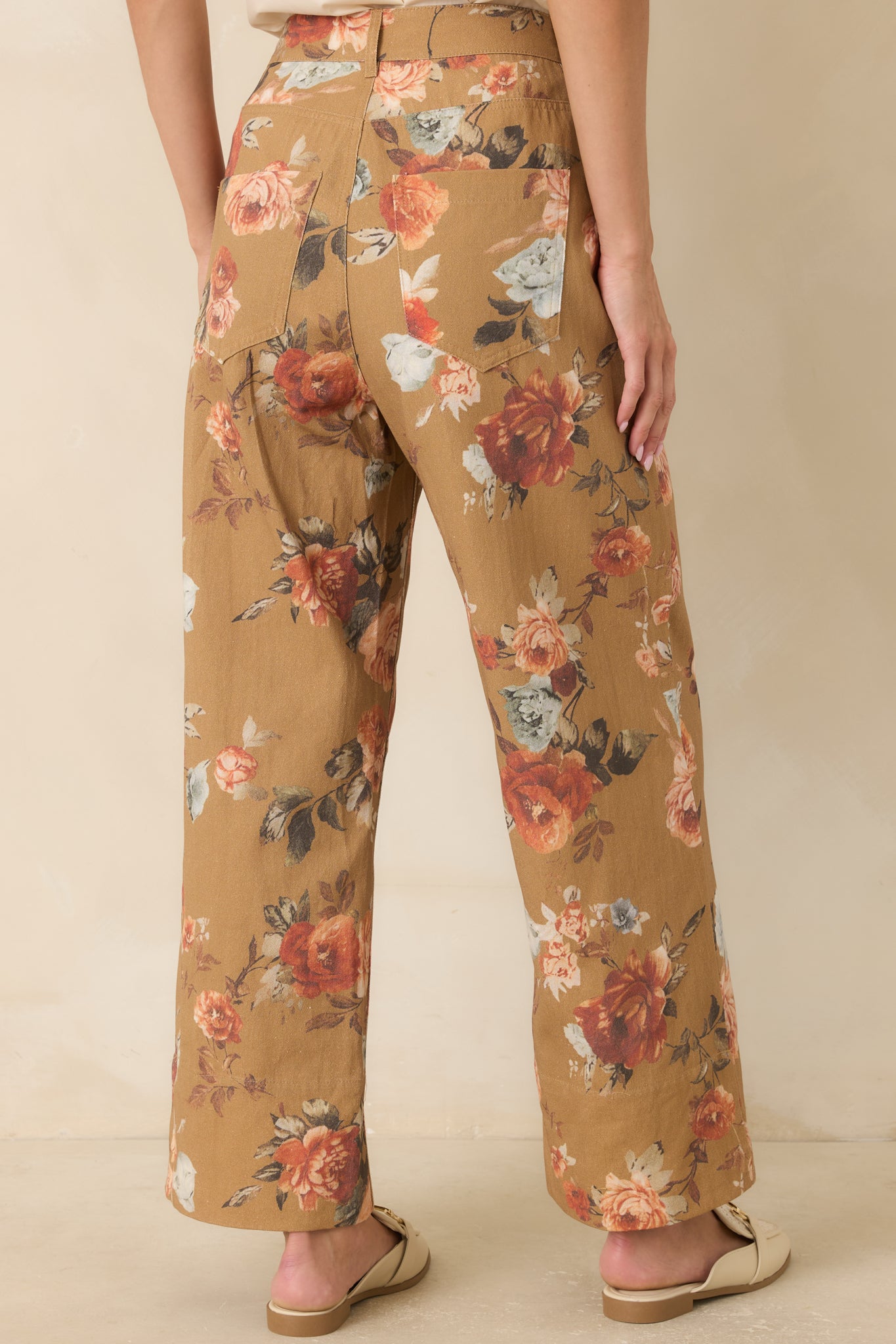 Back view of the camel floral pants featuring back patch pockets, wide legs, and a relaxed tailored silhouette.