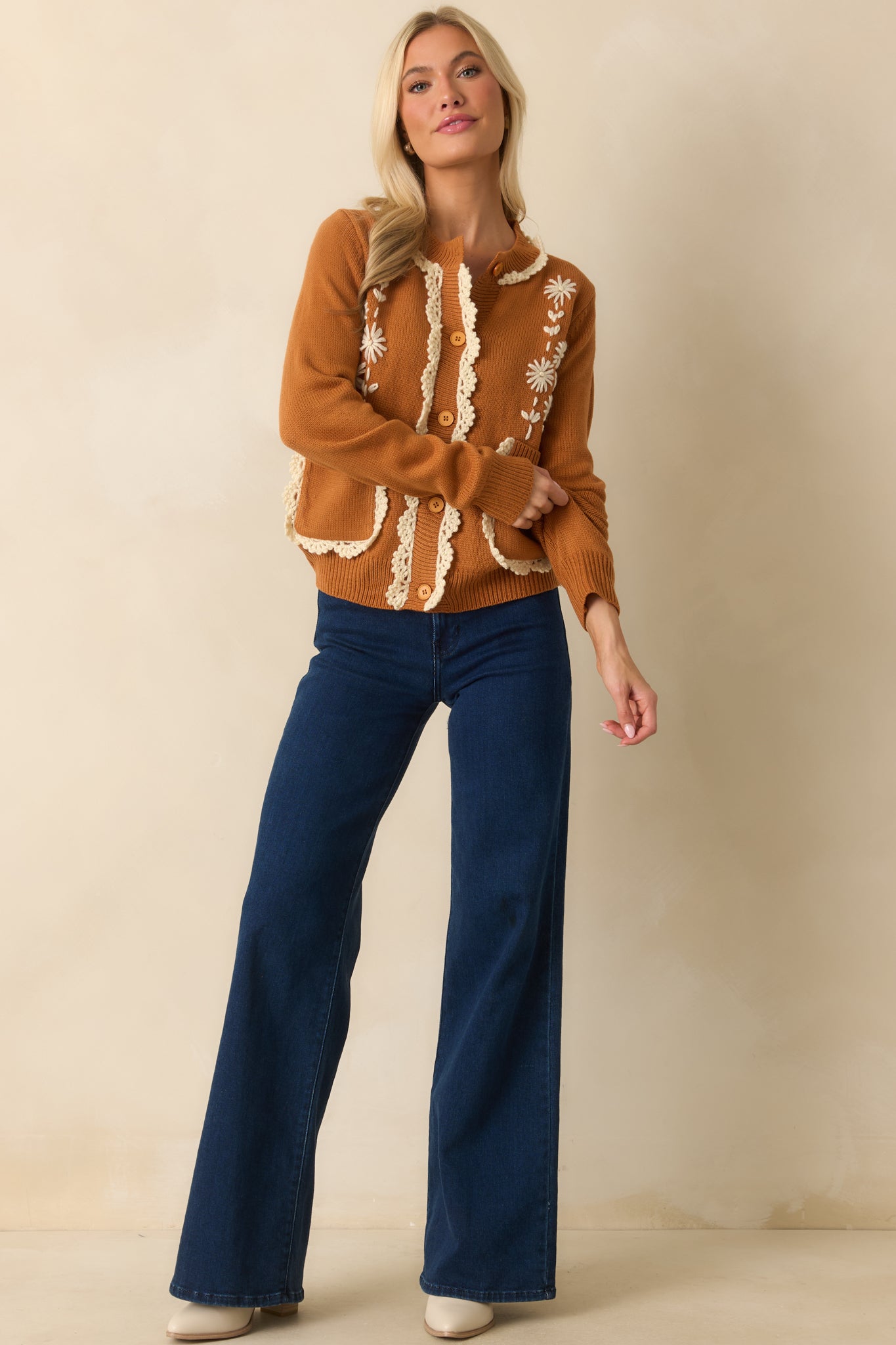 A full front view of the caramel brown cardigan with ivory daisy embroidery and scalloped crochet trim.