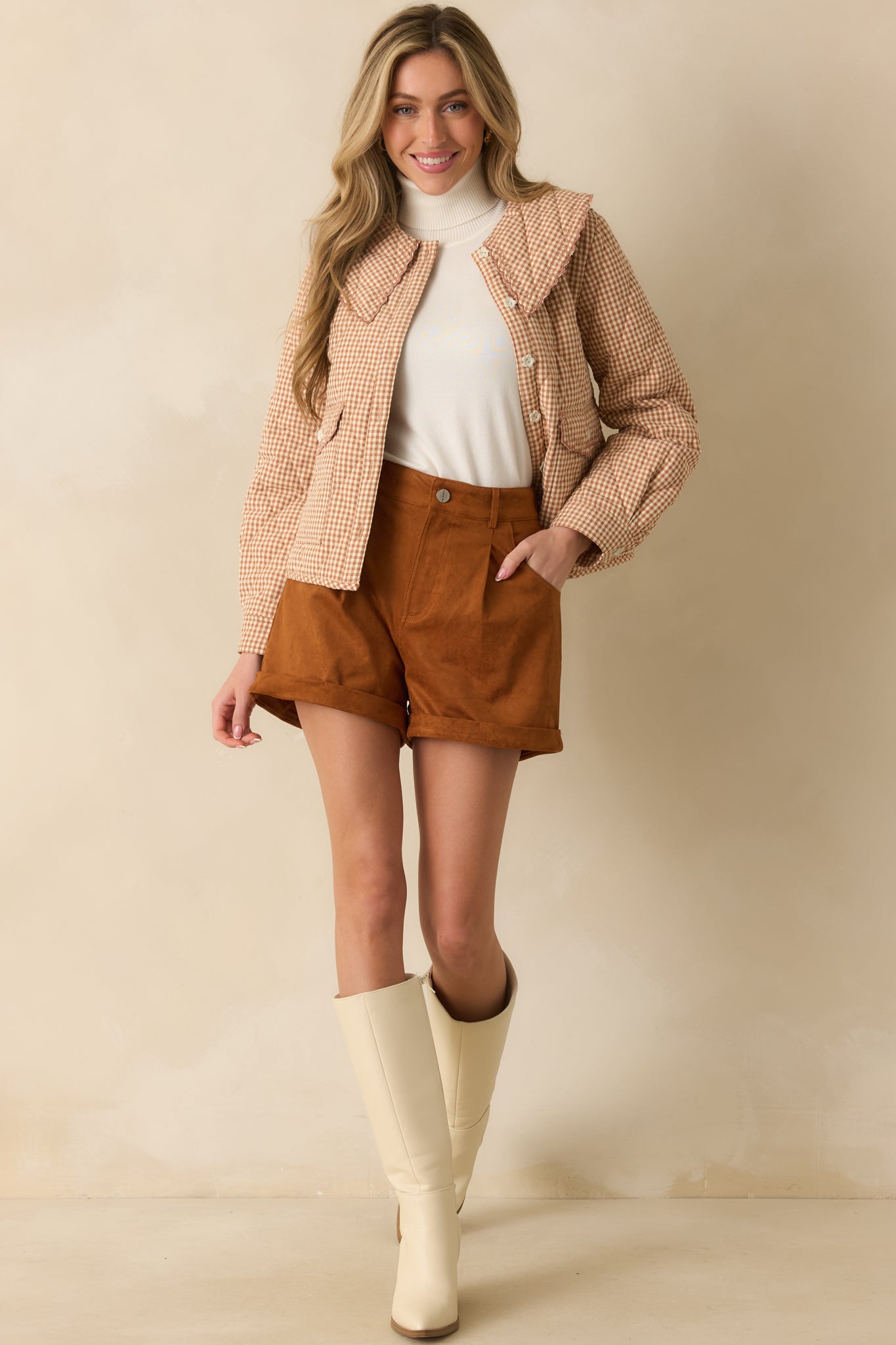 Full body front view of the caramel brown faux suede shorts with a high rise waist and rolled cuff hems.