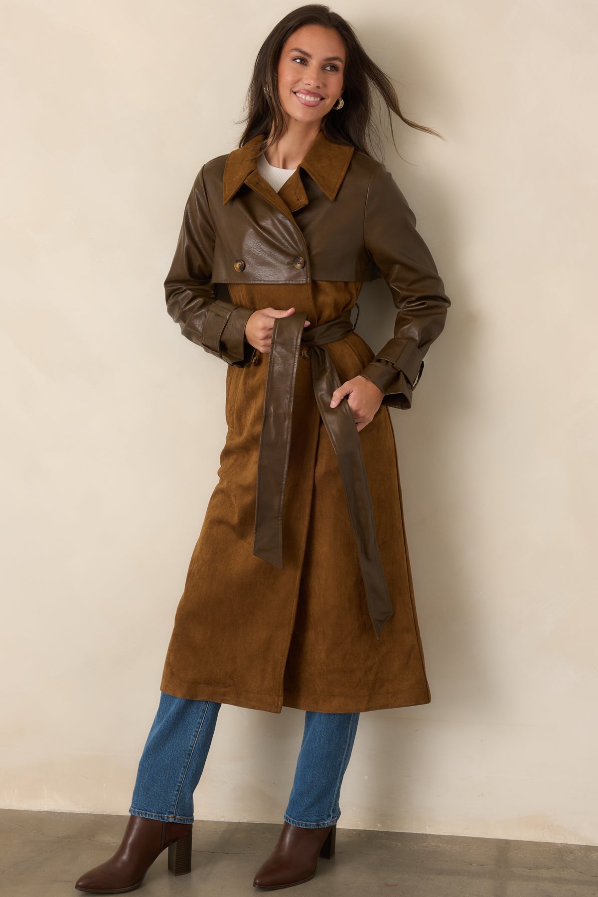 Caramel and brown materials create a striking two-tone trench silhouette with wide lapels and a coordinating waist belt.