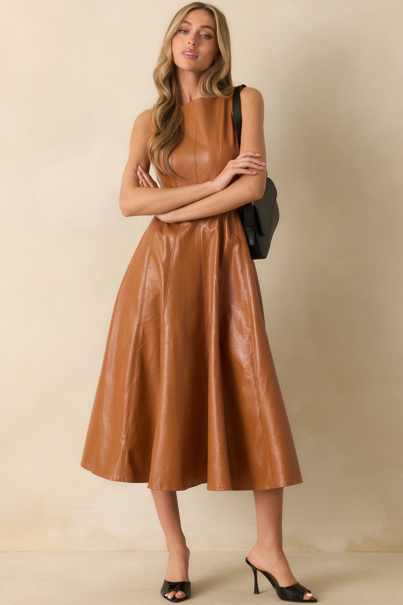 Caramel faux leather midi dress with a sleeveless bodice, paneled skirt, and belted waist for a structured look.