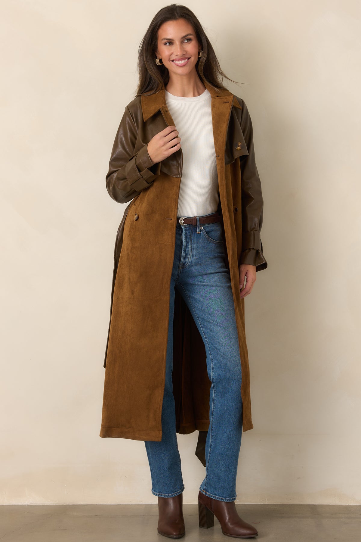 Smooth brown faux leather sleeves contrast with the warm caramel suede-look body, wide lapels, and long trench silhouette.
