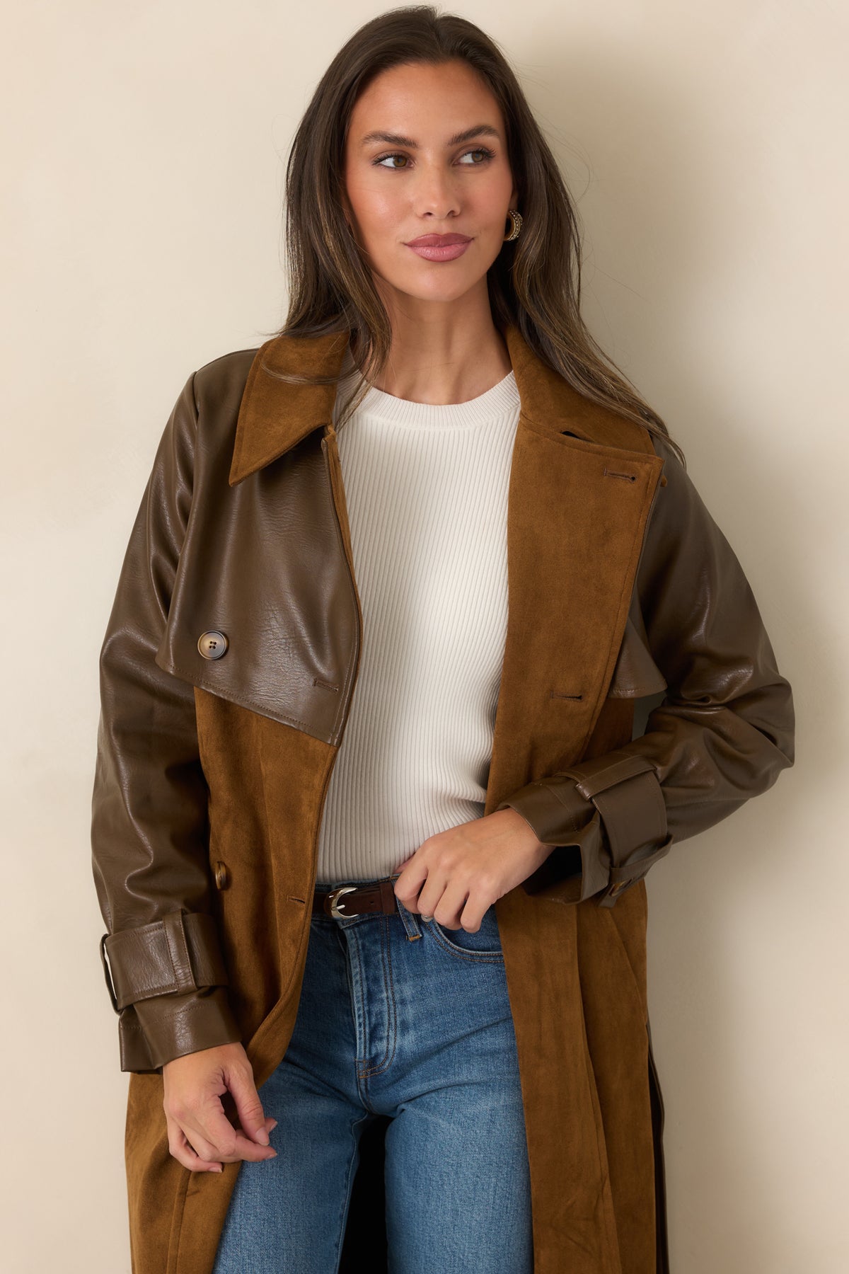 Wide caramel lapels frame the double-breasted front, highlighting the coat's classic structured trench design.