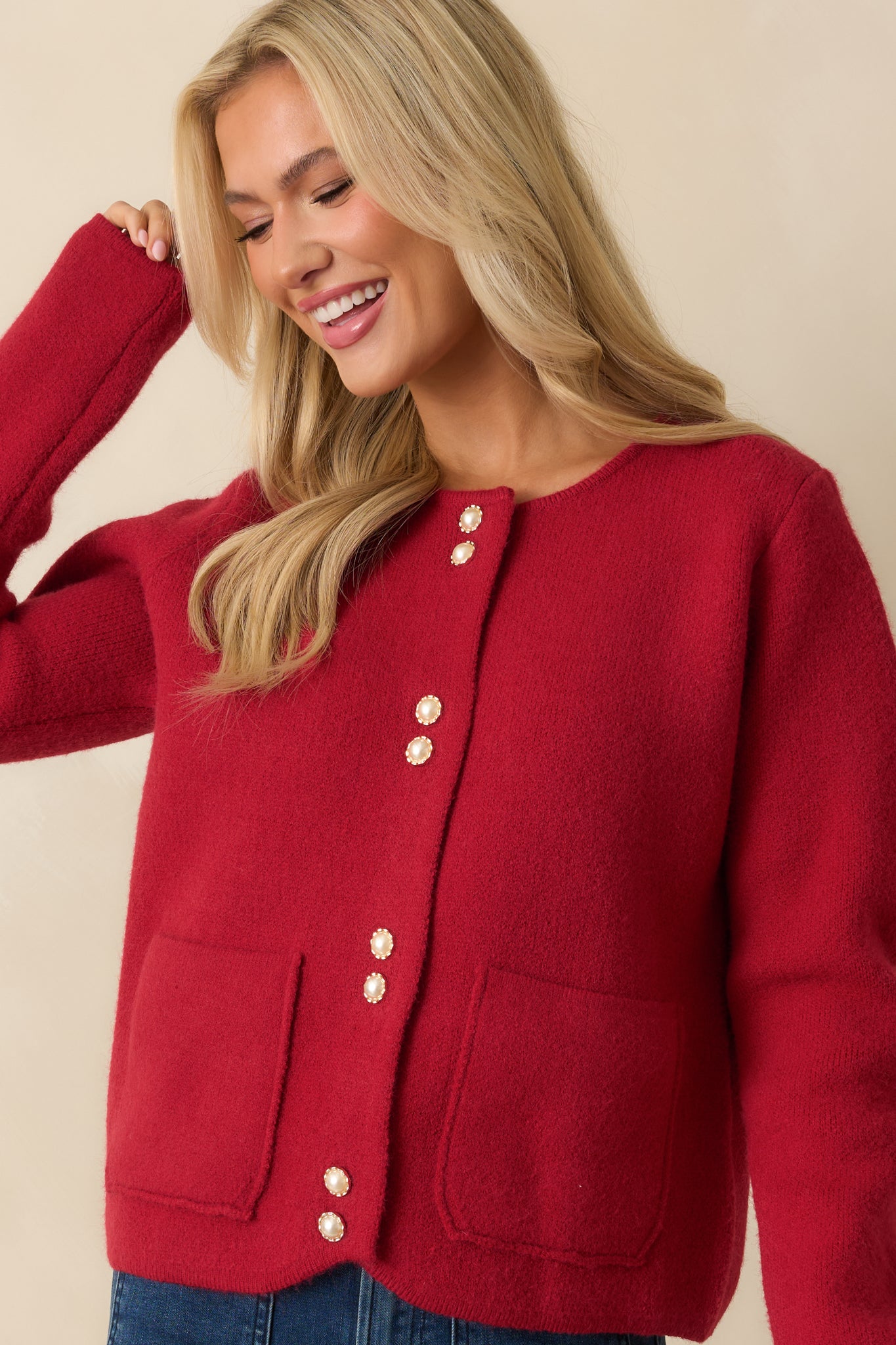 Close view of the cardigan’s round neckline, long sleeves, and pearl-accent buttons.