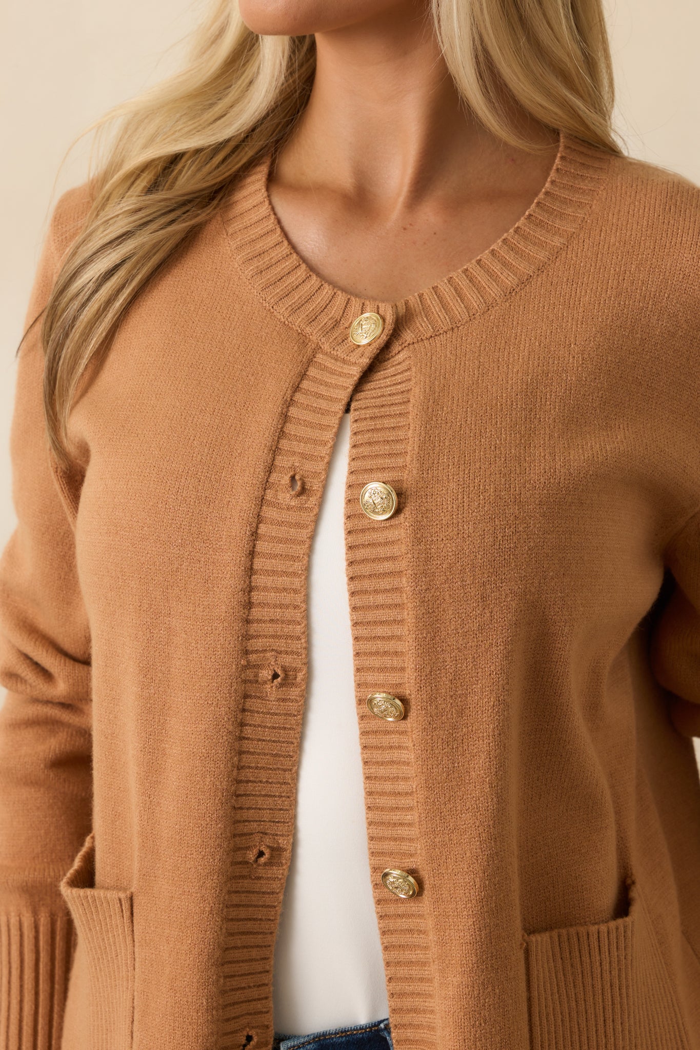 A detailed close-up of the embossed gold-tone buttons and ribbed knit trim.