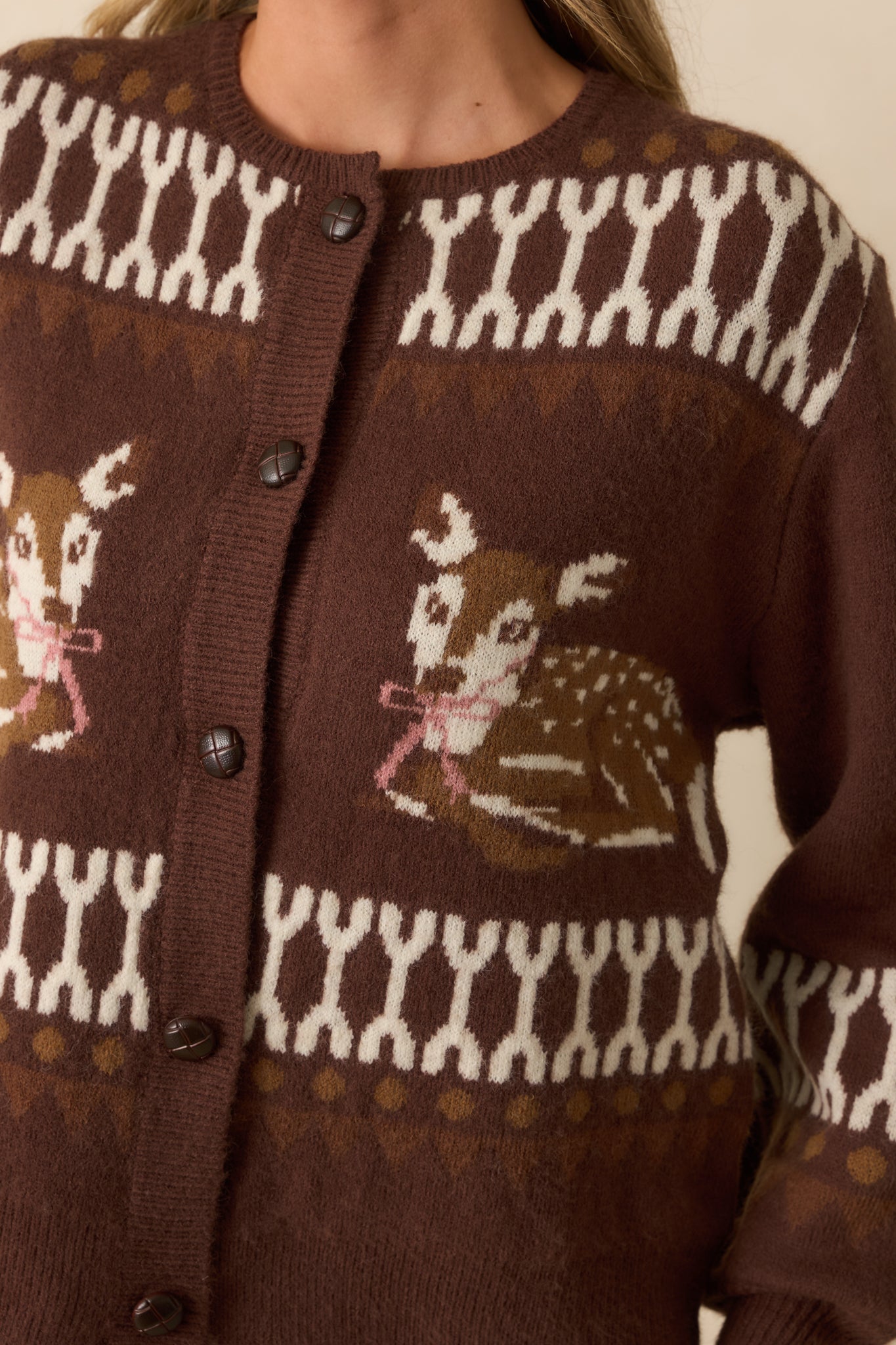 Detailed look at the intarsia deer motifs, geometric pattern, and button closures on the cardigan.