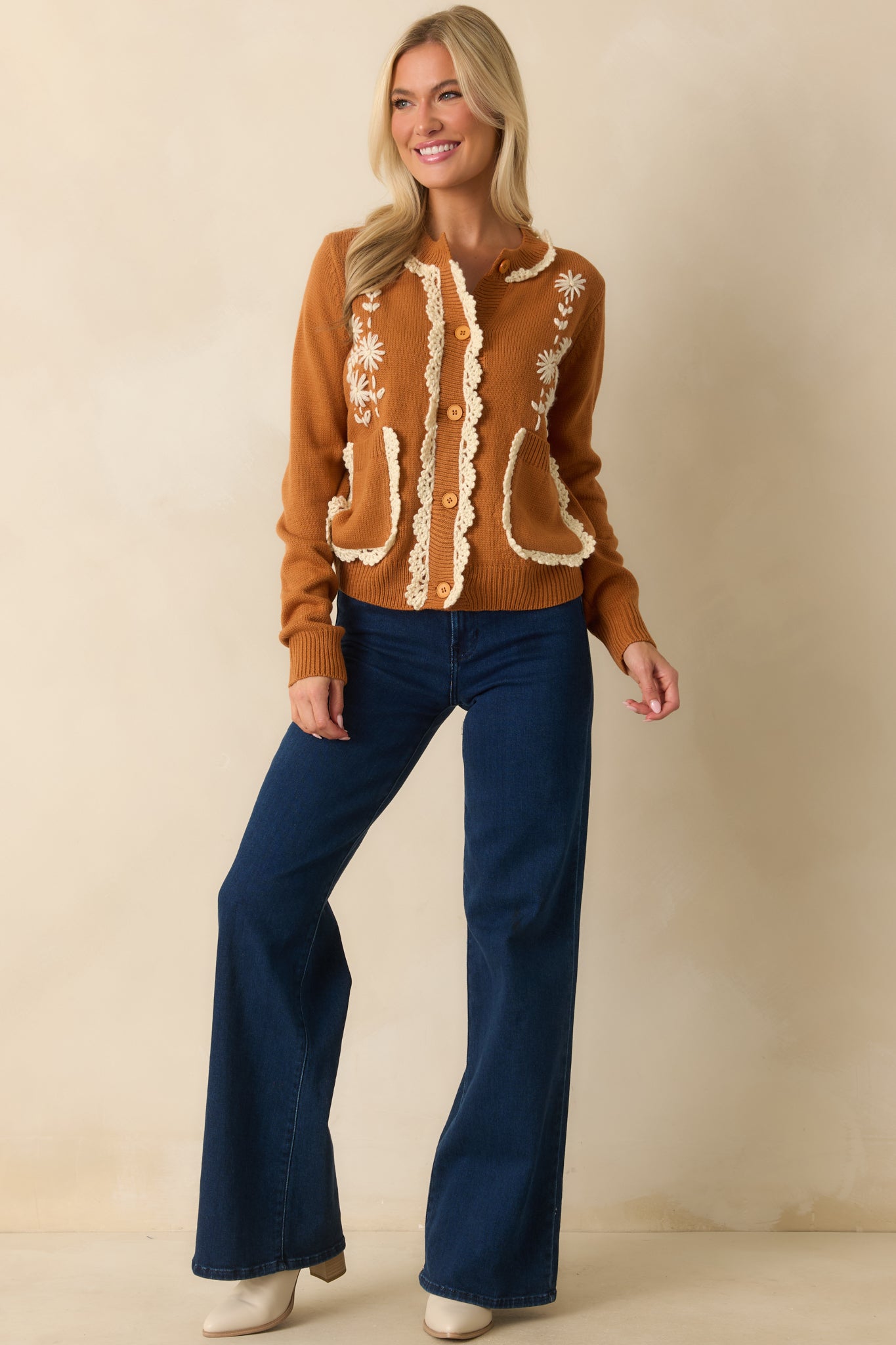 A front-facing full body shot highlighting the embroidered daisies and long sleeves with ribbed cuffs.