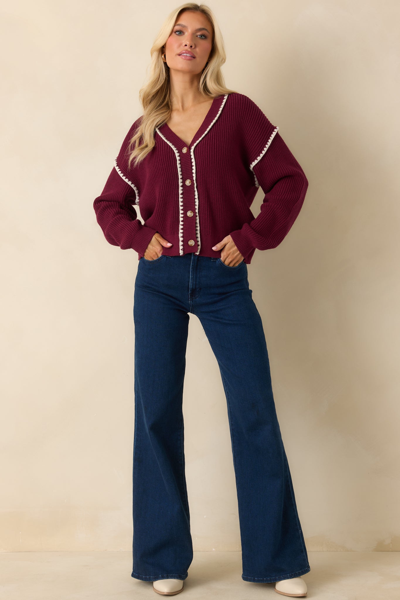 The cardigan highlights its long sleeves and contrasting whipstitch detail along the edges, emphasizing the relaxed fit.