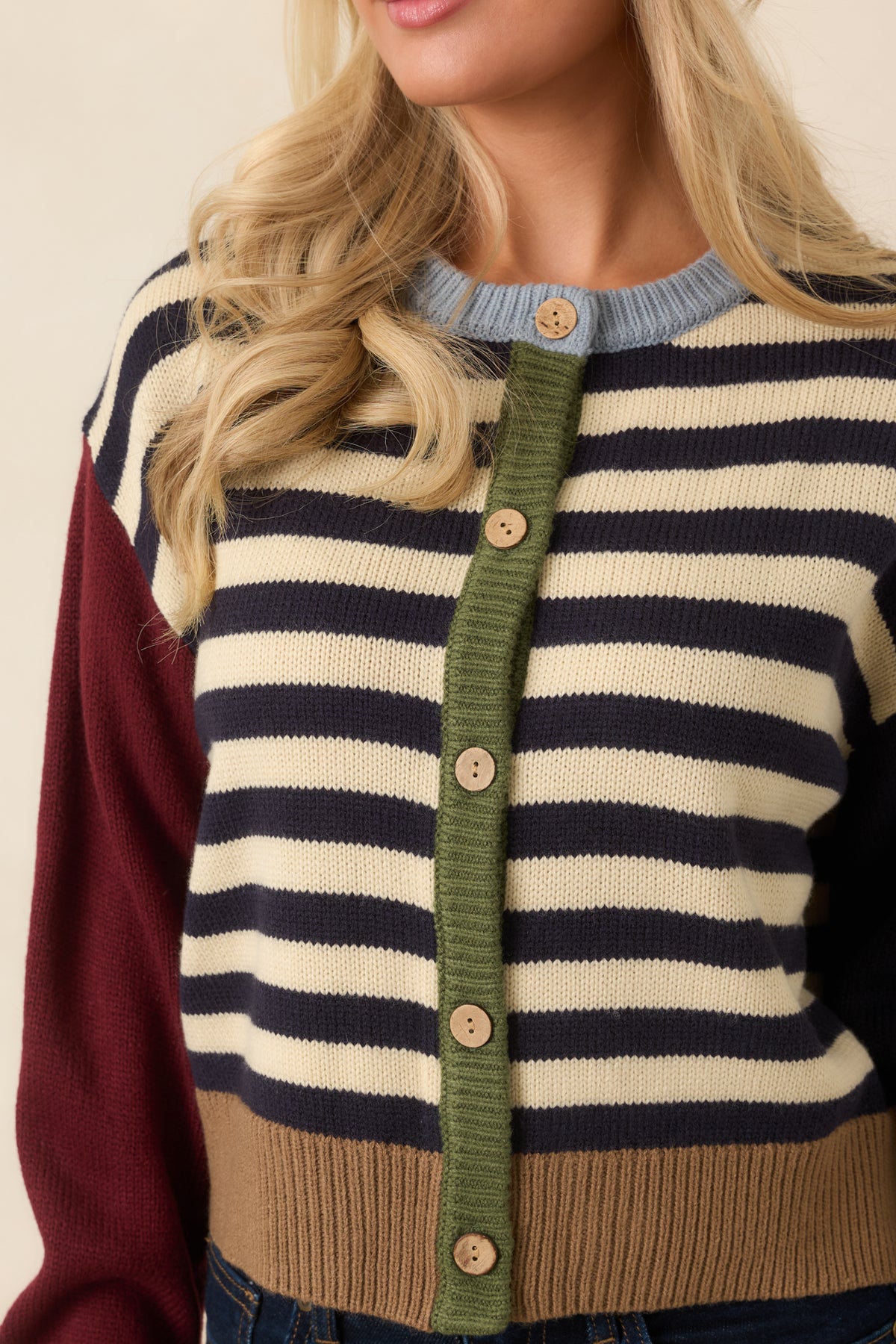Neutral buttons line the olive knit placket between the navy and ivory striped cardigan panels.