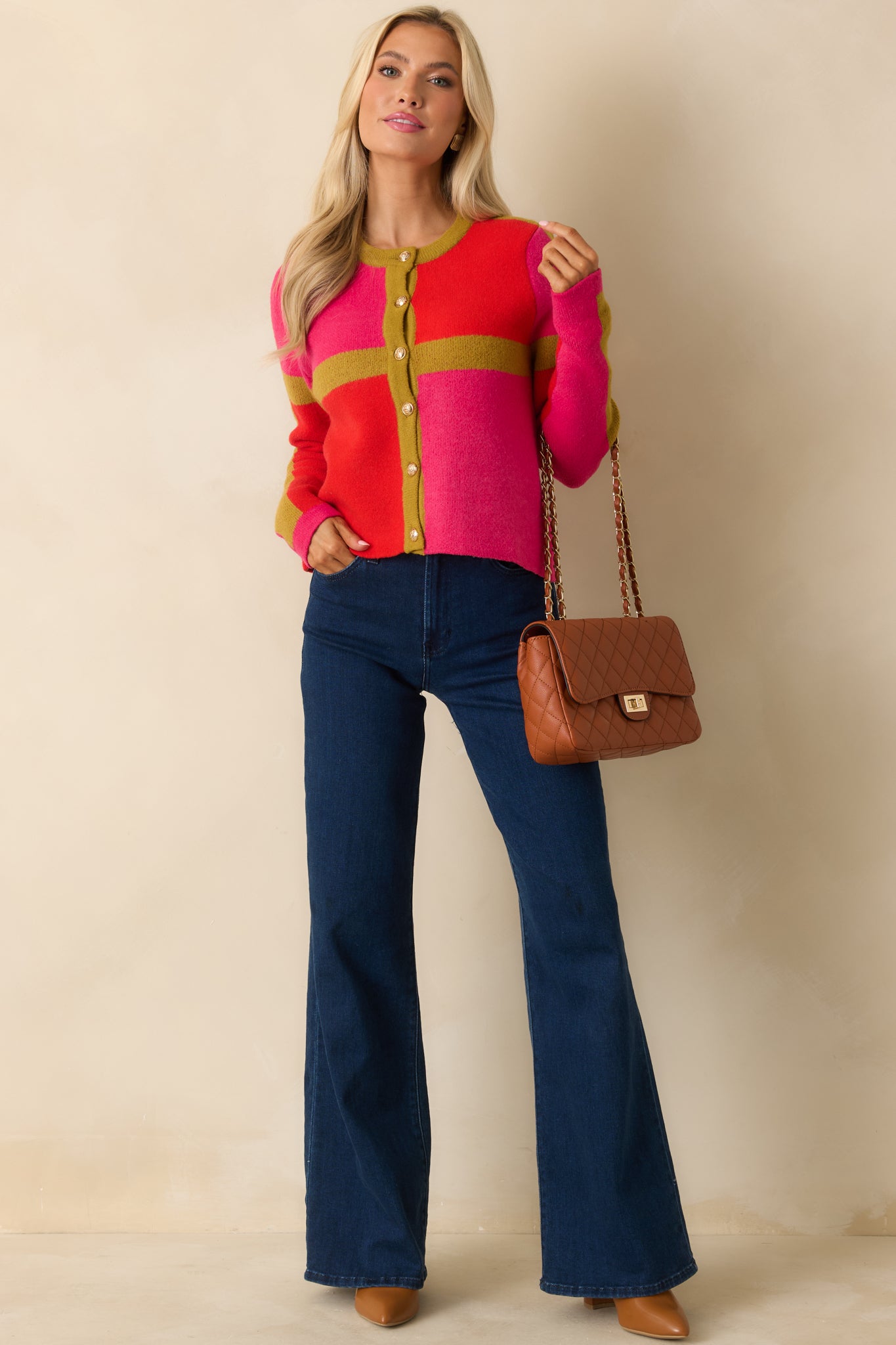 The cardigan showcases its pink, red, and olive color blocks with long sleeves, round neckline, and relaxed silhouette.