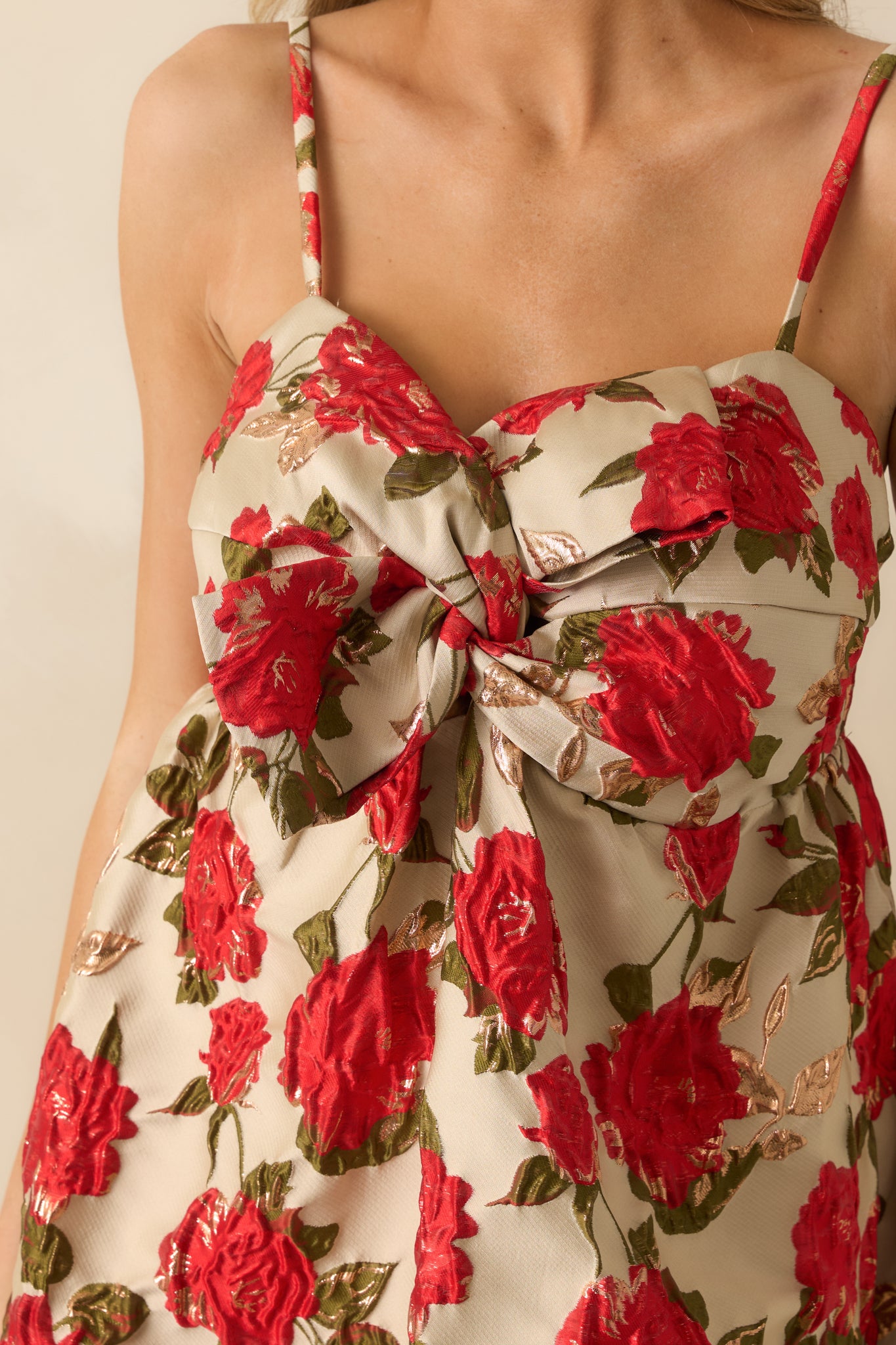 Detailed shot of the champagne mini dress showing the structural bow on the bodice, fabric texture, and adjustable straps.