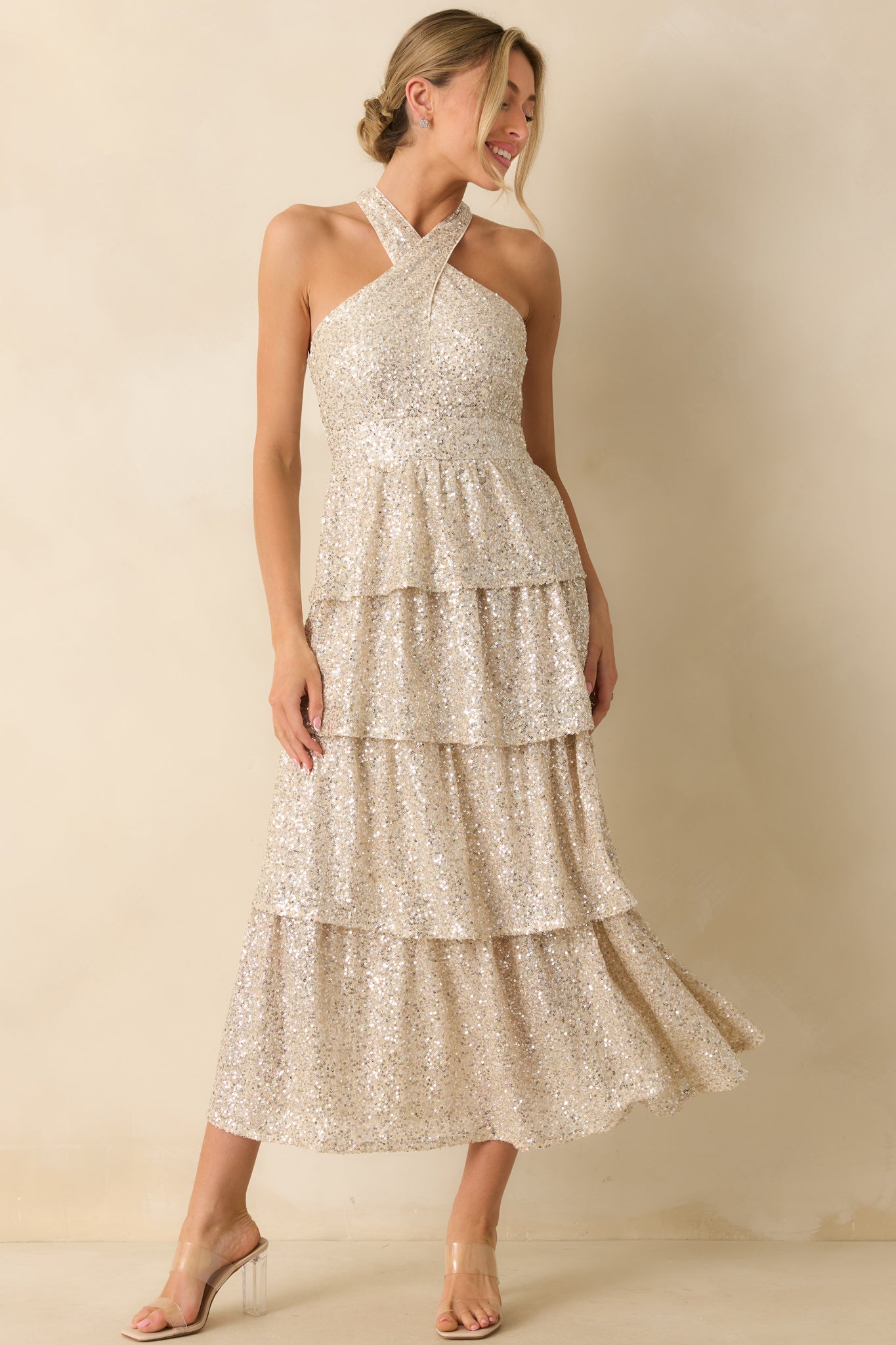 Champagne sequin maxi dress with a halter neckline and tiered skirt, shimmering elegantly from bodice to hem.