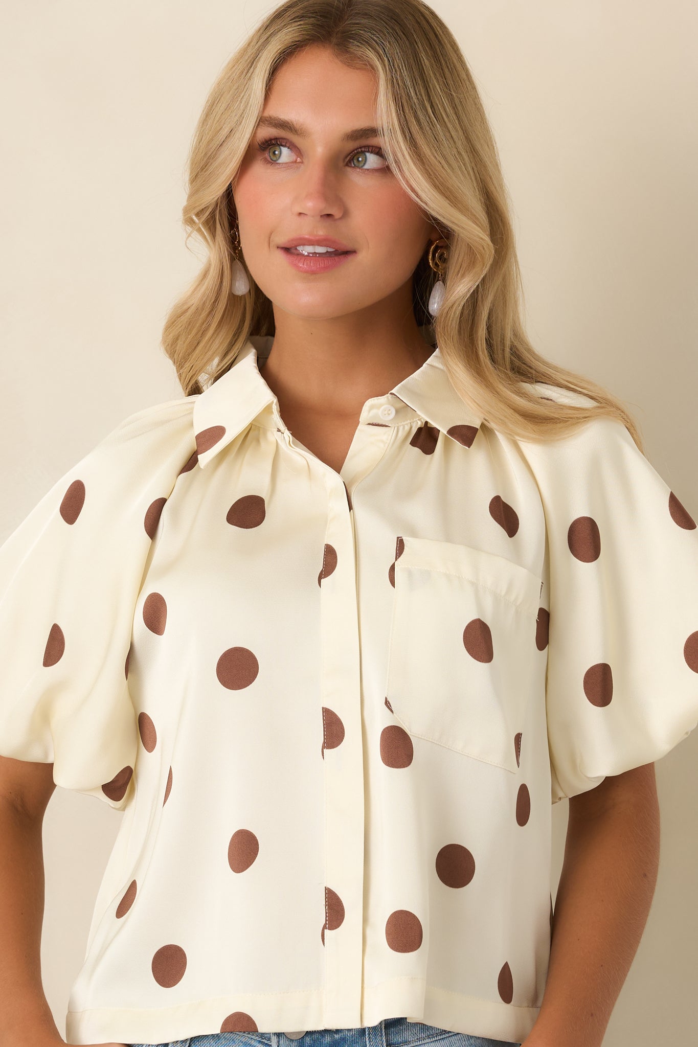 Single chest pocket adds a tailored touch to this silky ivory and brown polka dot blouse.
