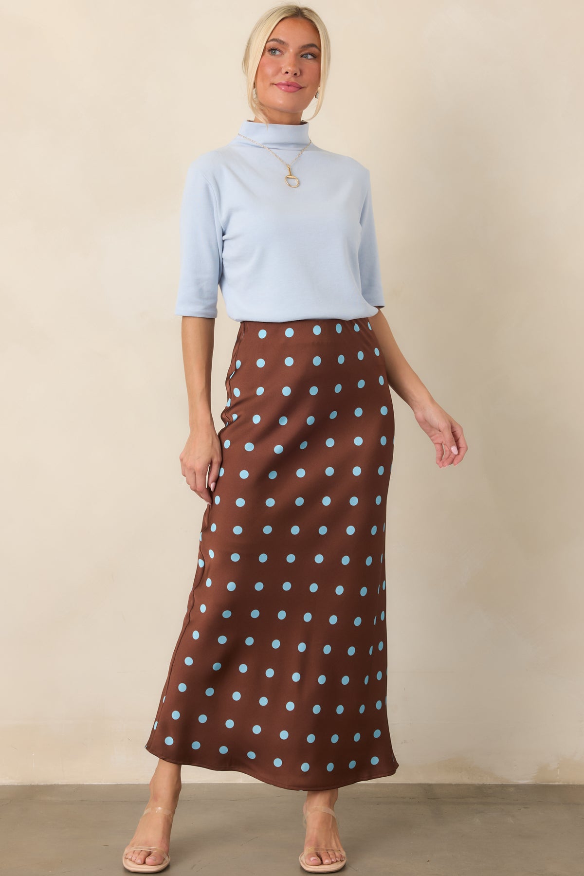 Bias-cut satin skirt with a rich chocolate brown base, delicate light blue dots, and a softly flowing midi-length shape.