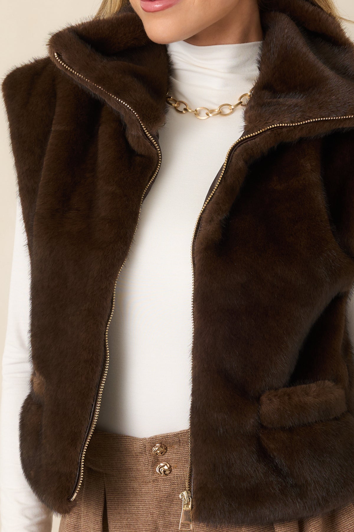 Close view of the silver-tone zipper and dense faux fur texture on the chocolate brown vest.