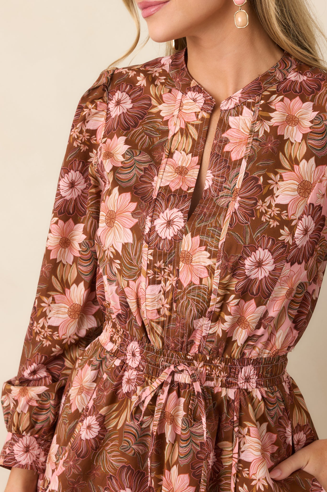 Close-up of the chocolate brown floral dress highlighting the split neckline, gathered fabric, and delicate pink, burgundy, and green blooms.