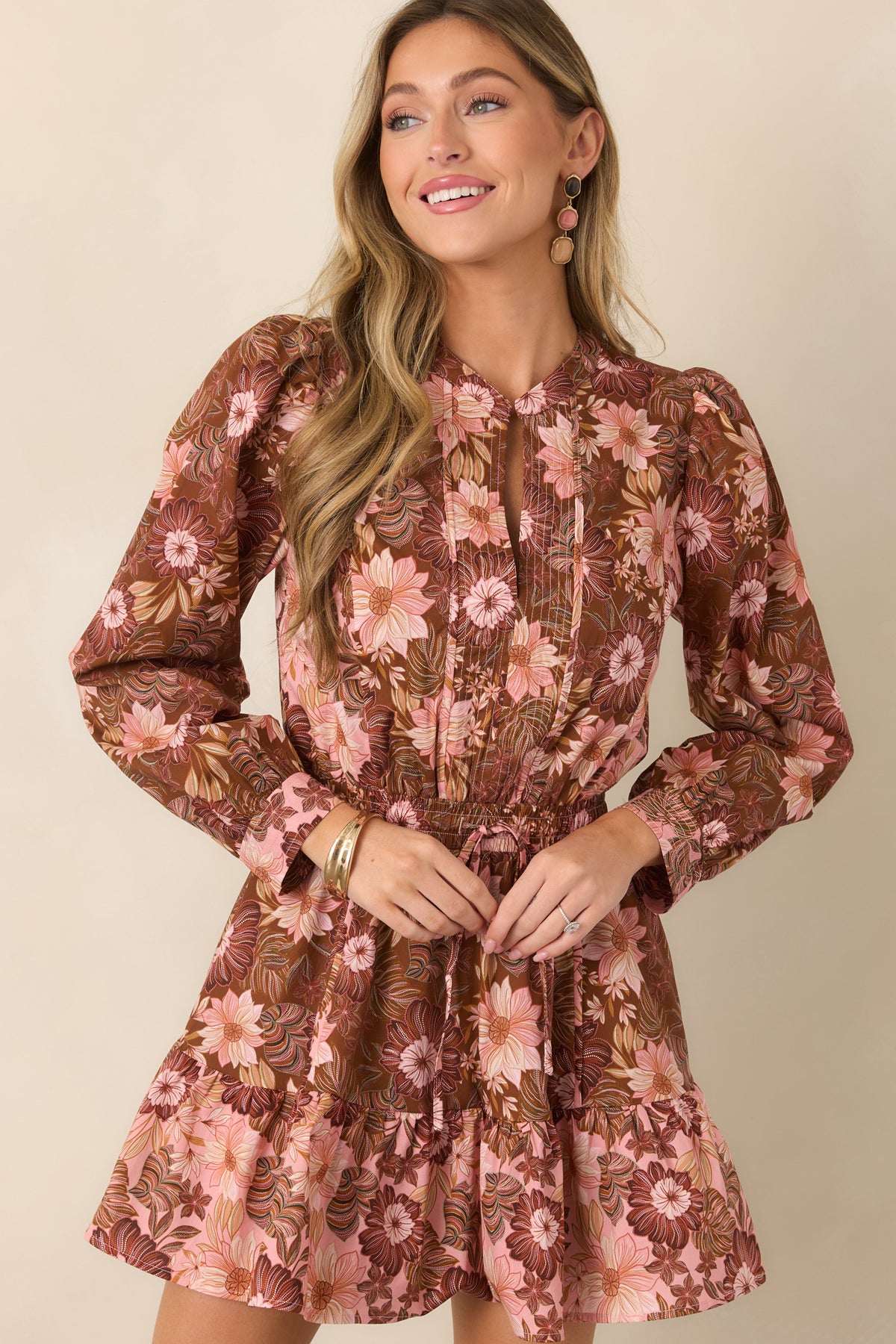 Chocolate brown floral dress highlighting the split neckline, gathered drawstring waist, and long sleeves finished with button cuffs.