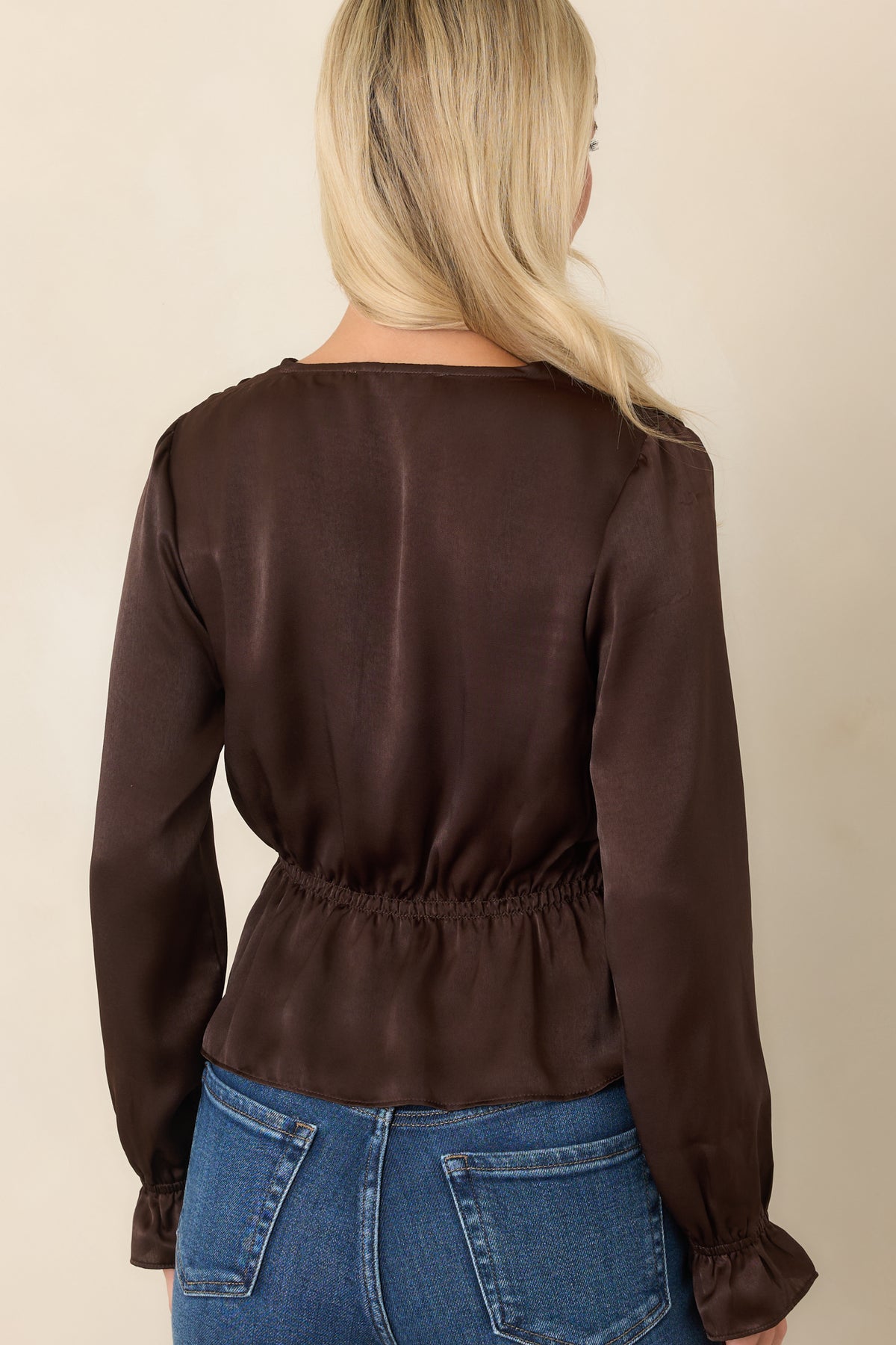 Rear view of the chocolate brown blouse showing the gathered shoulders, voluminous poet sleeves, adjustable waist, and softly flared peplum hem.