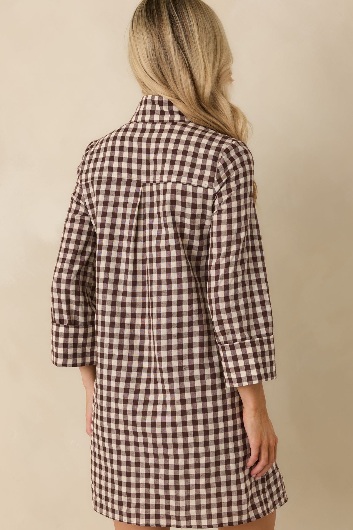 Rear view of the chocolate brown and ivory gingham mini dress showing its relaxed A-line silhouette.