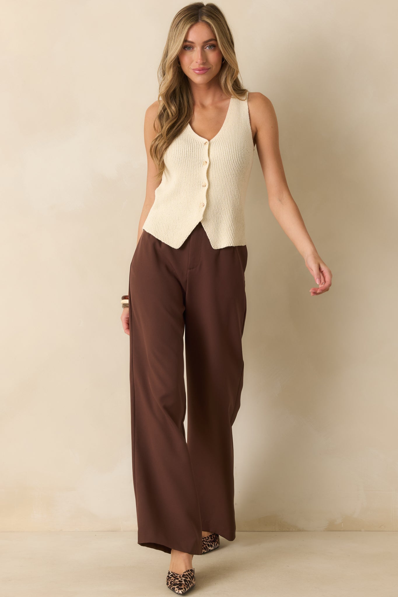 Chocolate brown pants with high-rise waist, pleated leg design, and hook-and-bar closure.