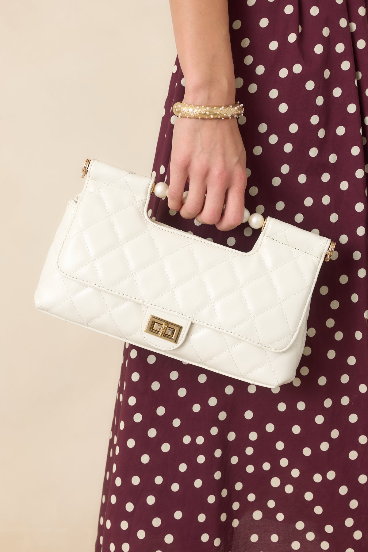 Structured handbag featuring smooth faux leather and a pearl top handle.