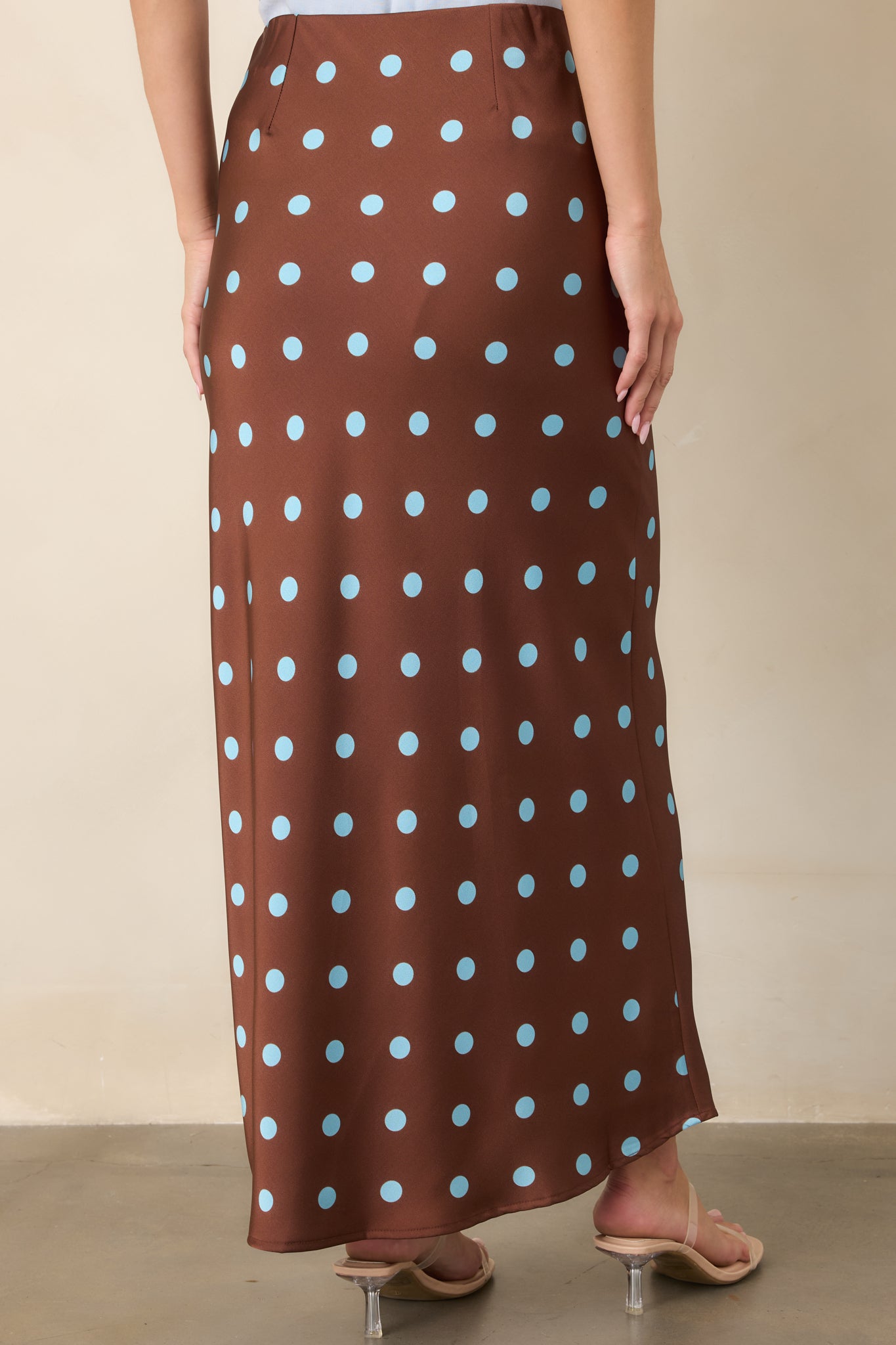 Rear view of the chocolate brown satin skirt featuring light blue polka dots, an elastic waistband, and fluid bias-cut drape.