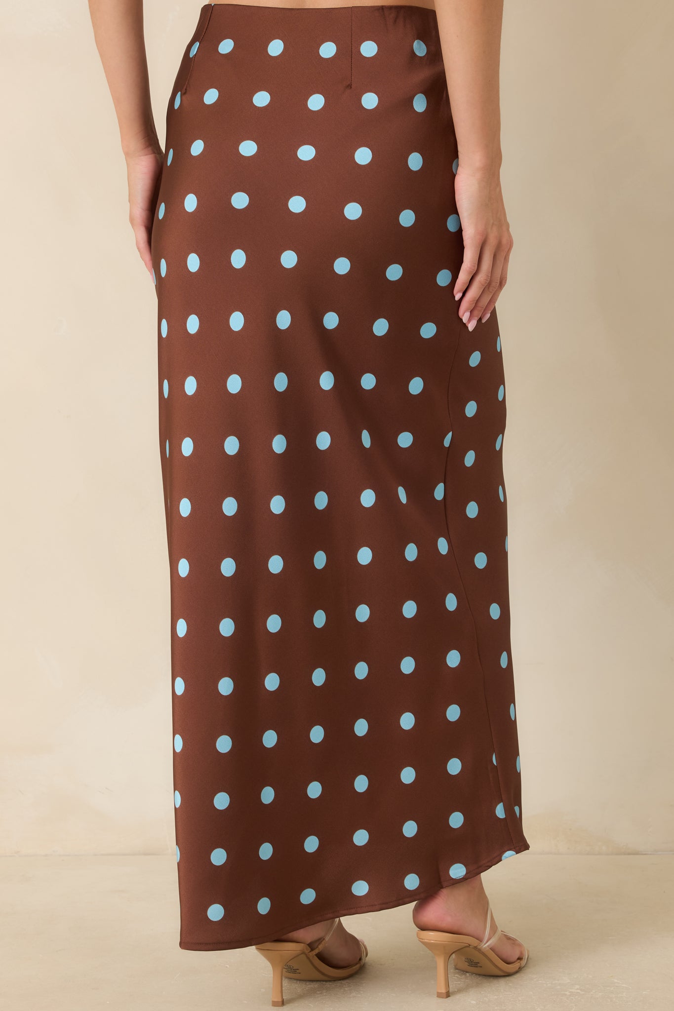 Chocolate brown satin skirt showing the back of the bias-cut silhouette with a flowing shape and comfortable elastic waistband.