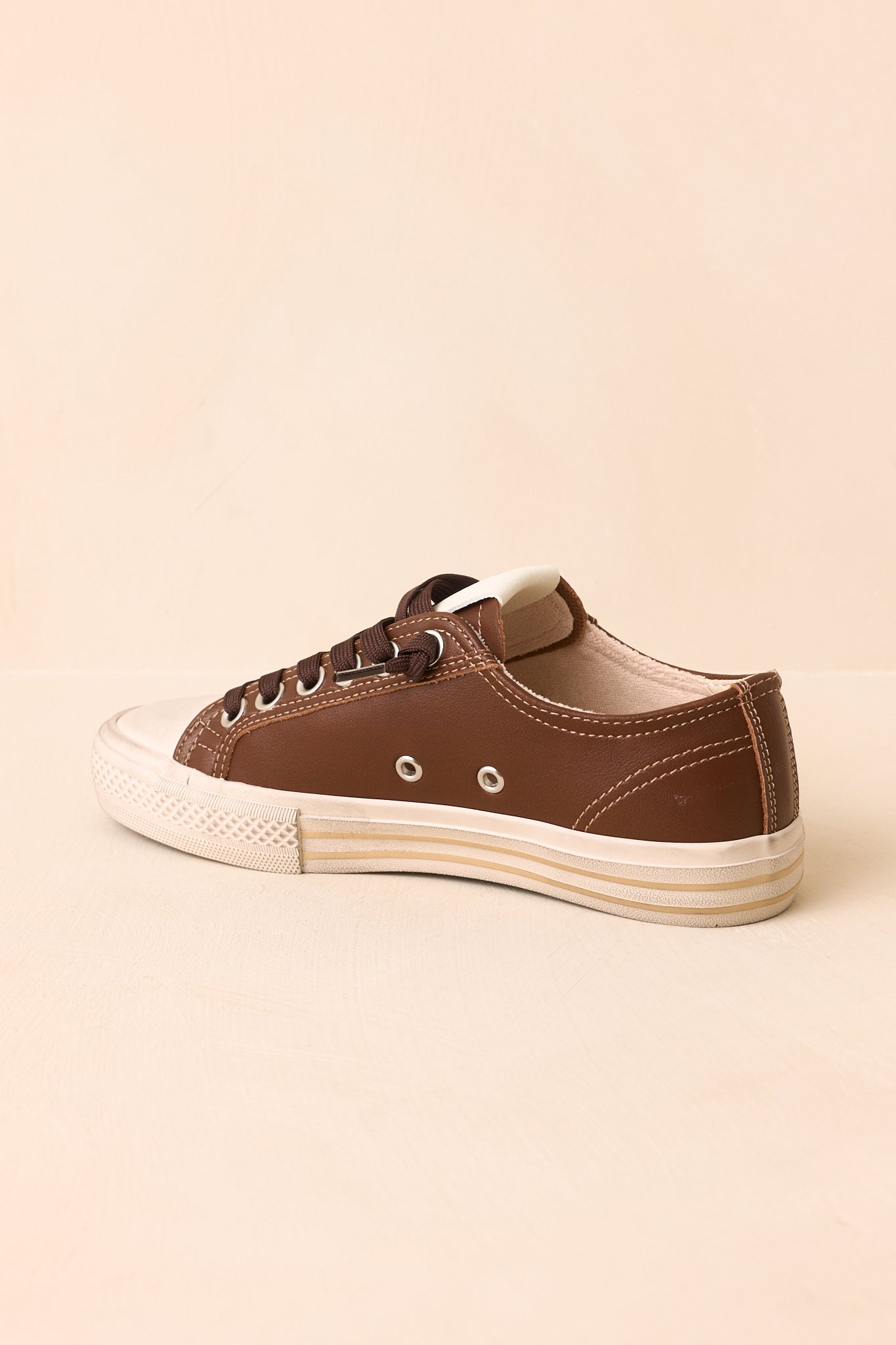 Chocolate brown sneakers showcasing contrast stitching and a textured mix of premium materials