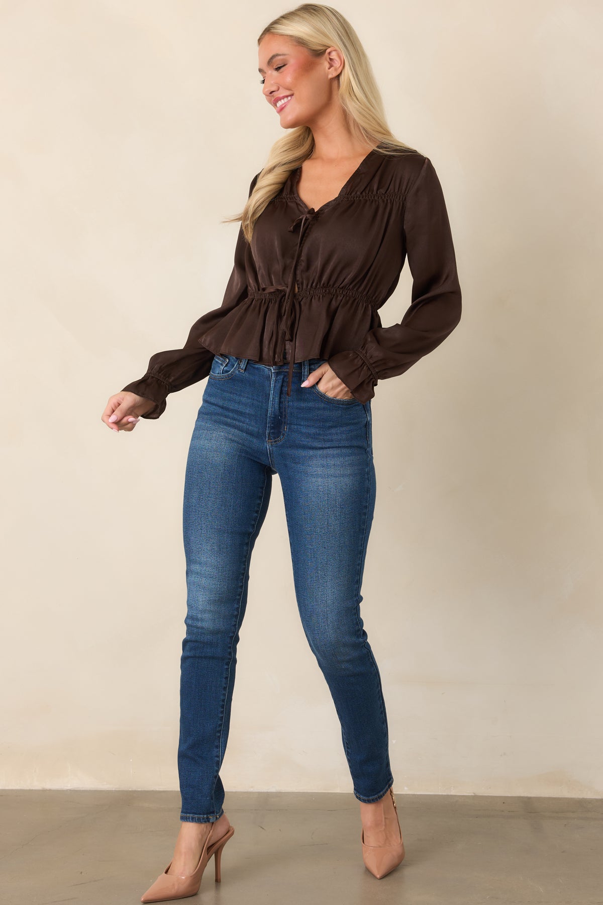 Deep chocolate brown blouse with a plunging V-neckline, delicate tie-front detail, voluminous poet sleeves, and a softly flared peplum hem.