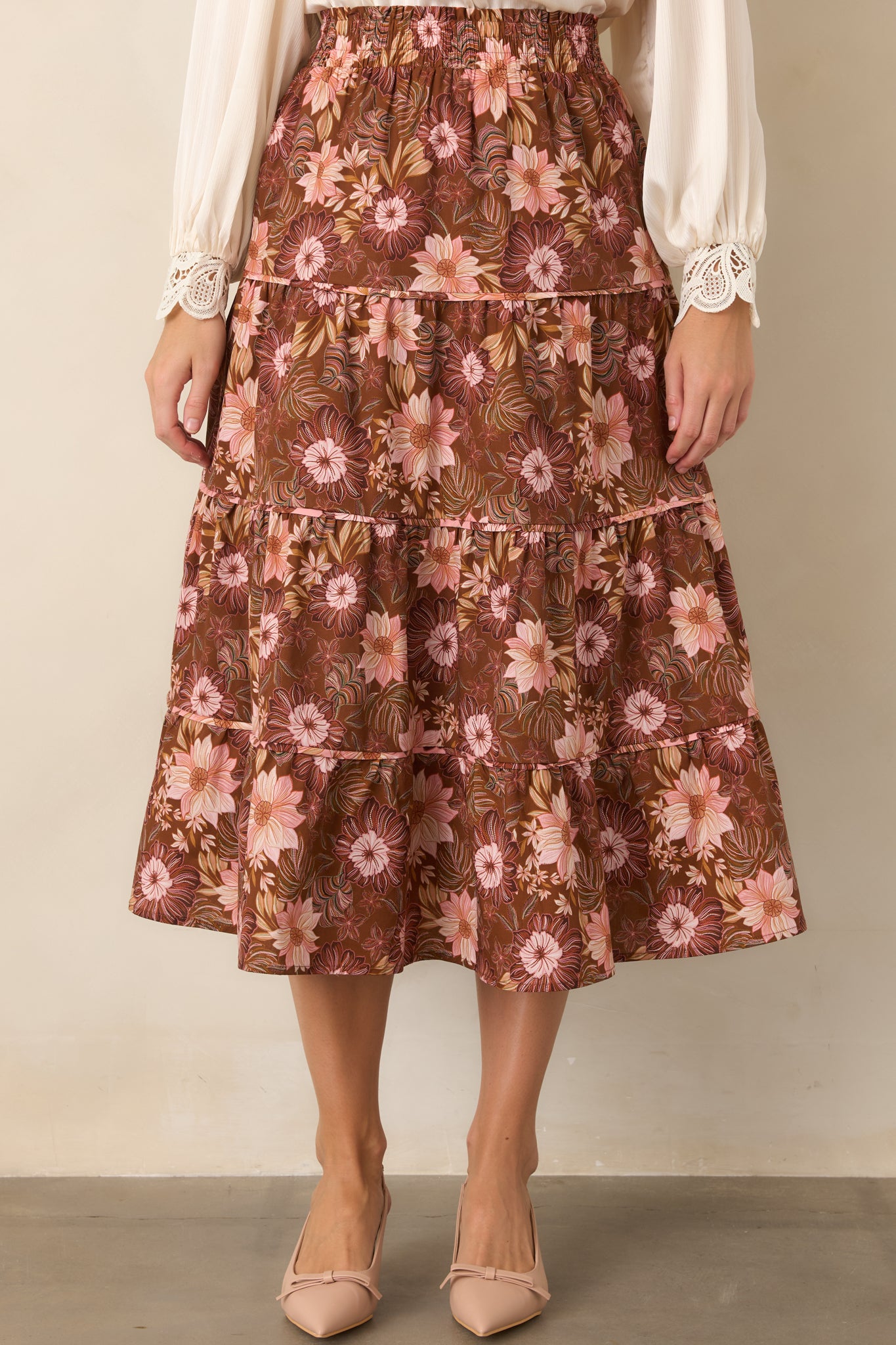 Close view of the tiered chocolate brown midi skirt, highlighting the pink, burgundy, and muted green floral print across its flowing layers.
