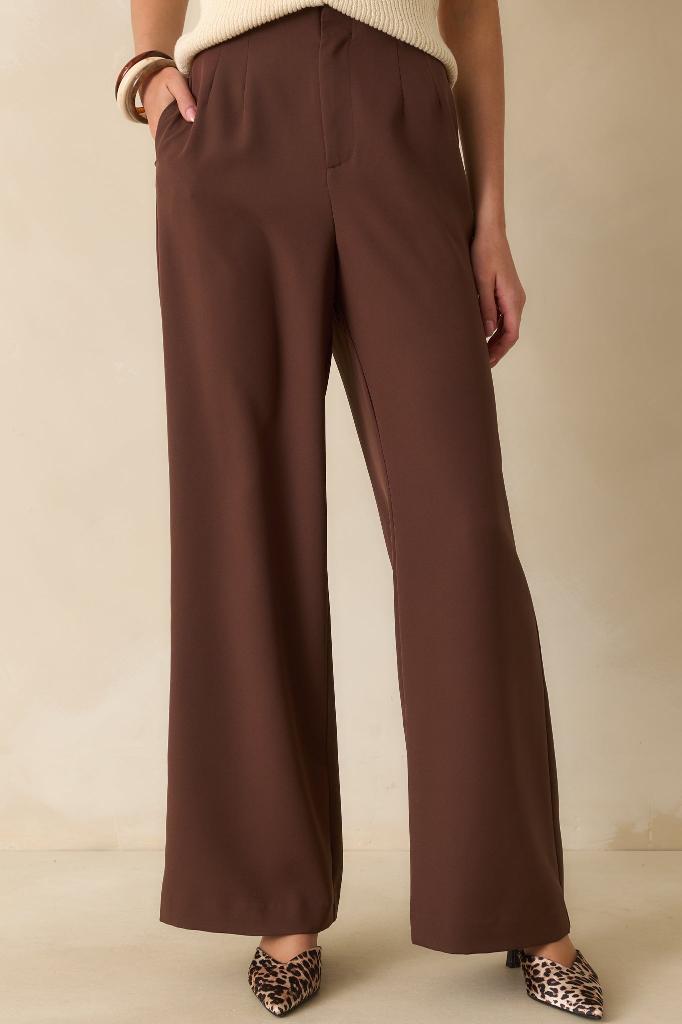 Pleated front and side pocket detail of the chocolate brown trousers.