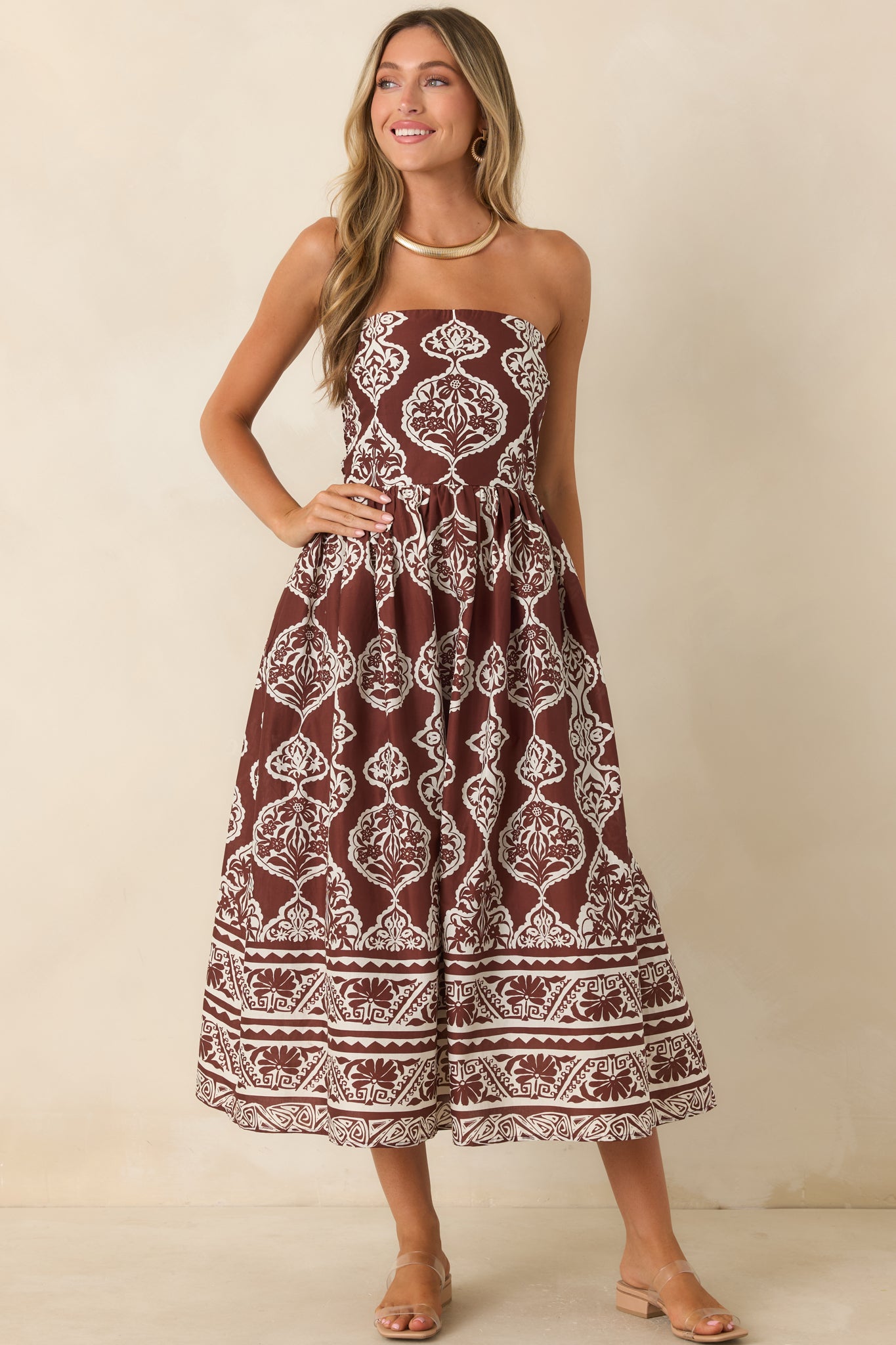 Chocolate brown and ivory medallion print midi dress featuring a strapless fitted bodice, gathered skirt, and border hem detail.