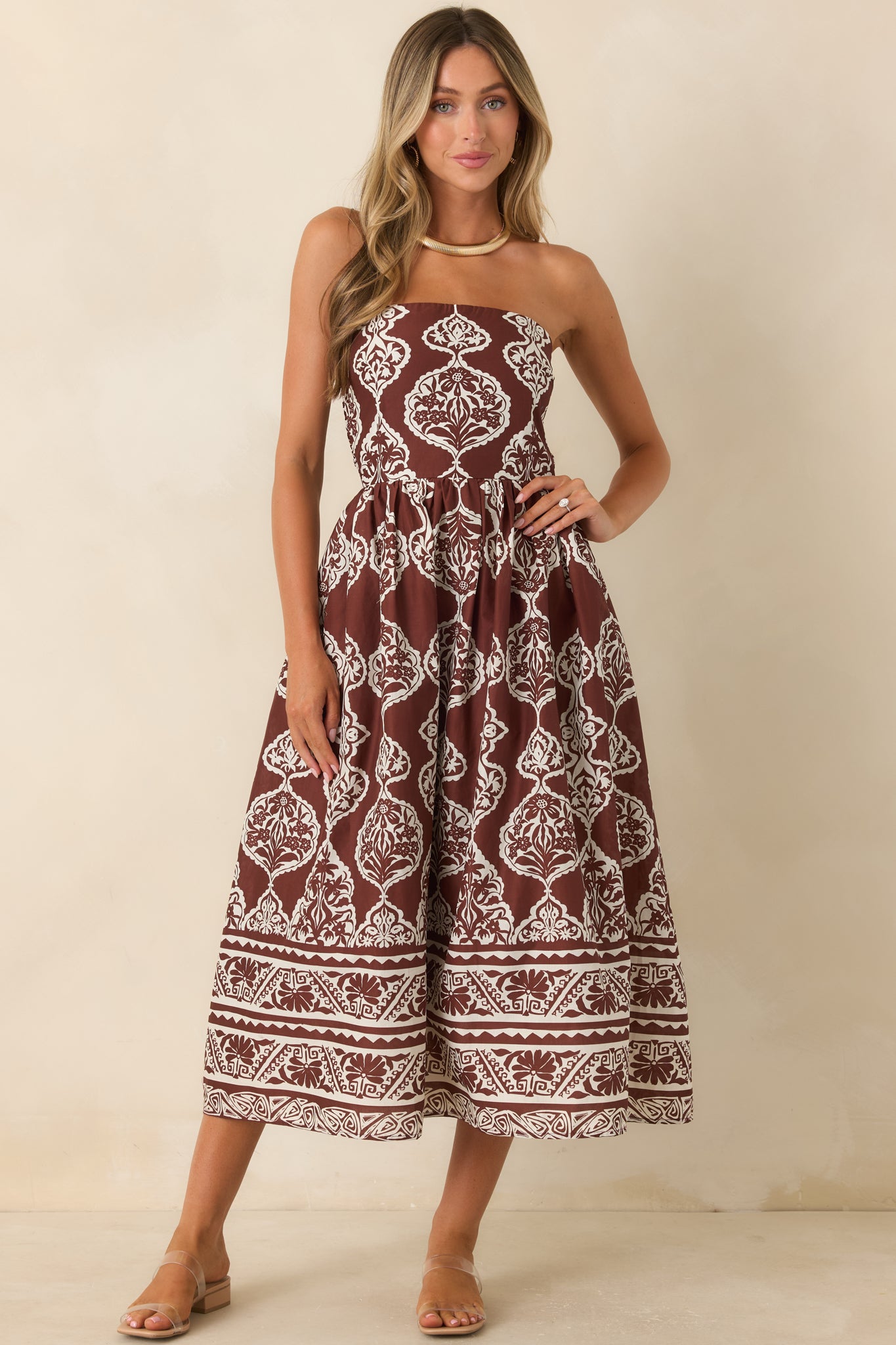 Chocolate brown and ivory printed midi dress featuring a strapless neckline, gathered skirt, and coordinating border hem.