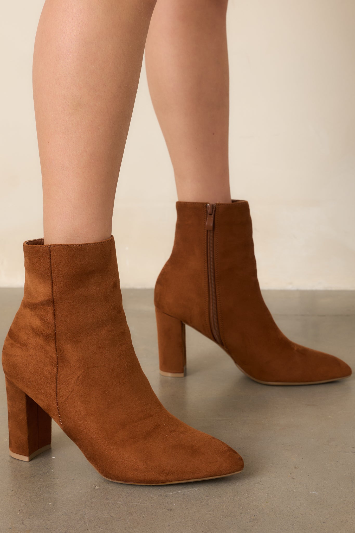 Cinnamon faux suede ankle boots showcasing a sleek pointed-toe silhouette, clean outer seams, and sturdy block heels.